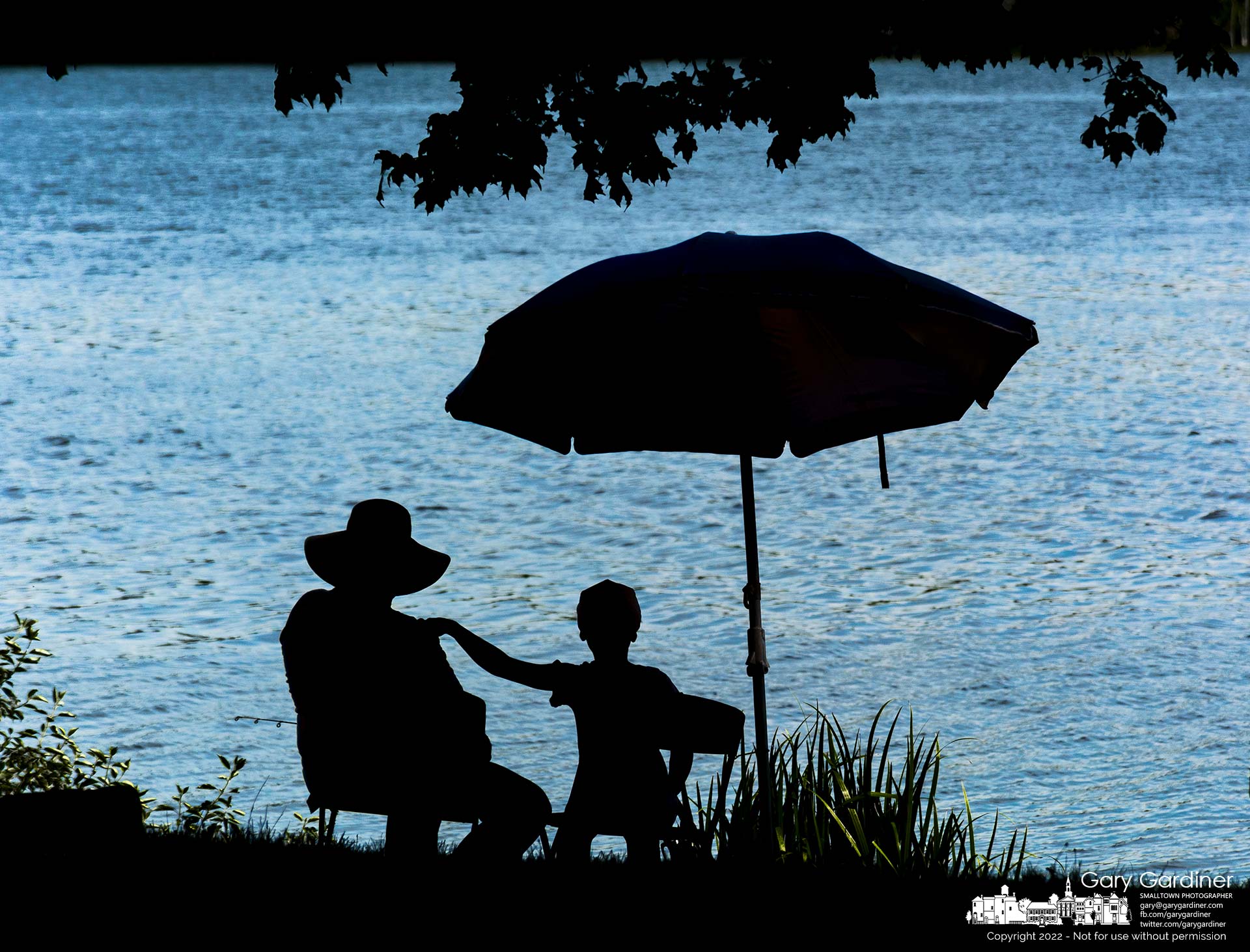 A young boy places his hand on his father's shoulder as they watch their fishing lines tossed into Hoover Reservoir from the shoreline at Red Bank Park. My Final Photo for July 30, 2022.