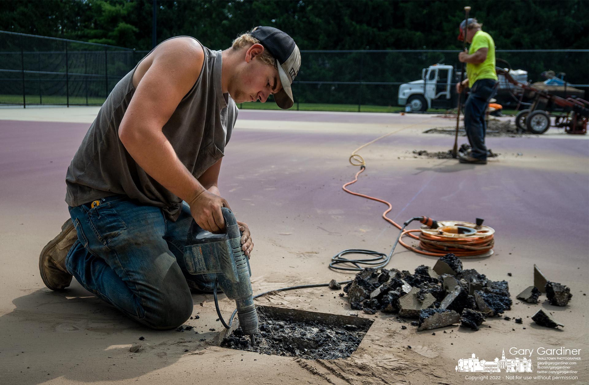 A worker removes asphalt and gravel for the new location for posts at the recently resurfaced tennis courts on South Otterbein after discovering the original holes were out of alignment with the court. My Final Photo for July 20, 2022.
