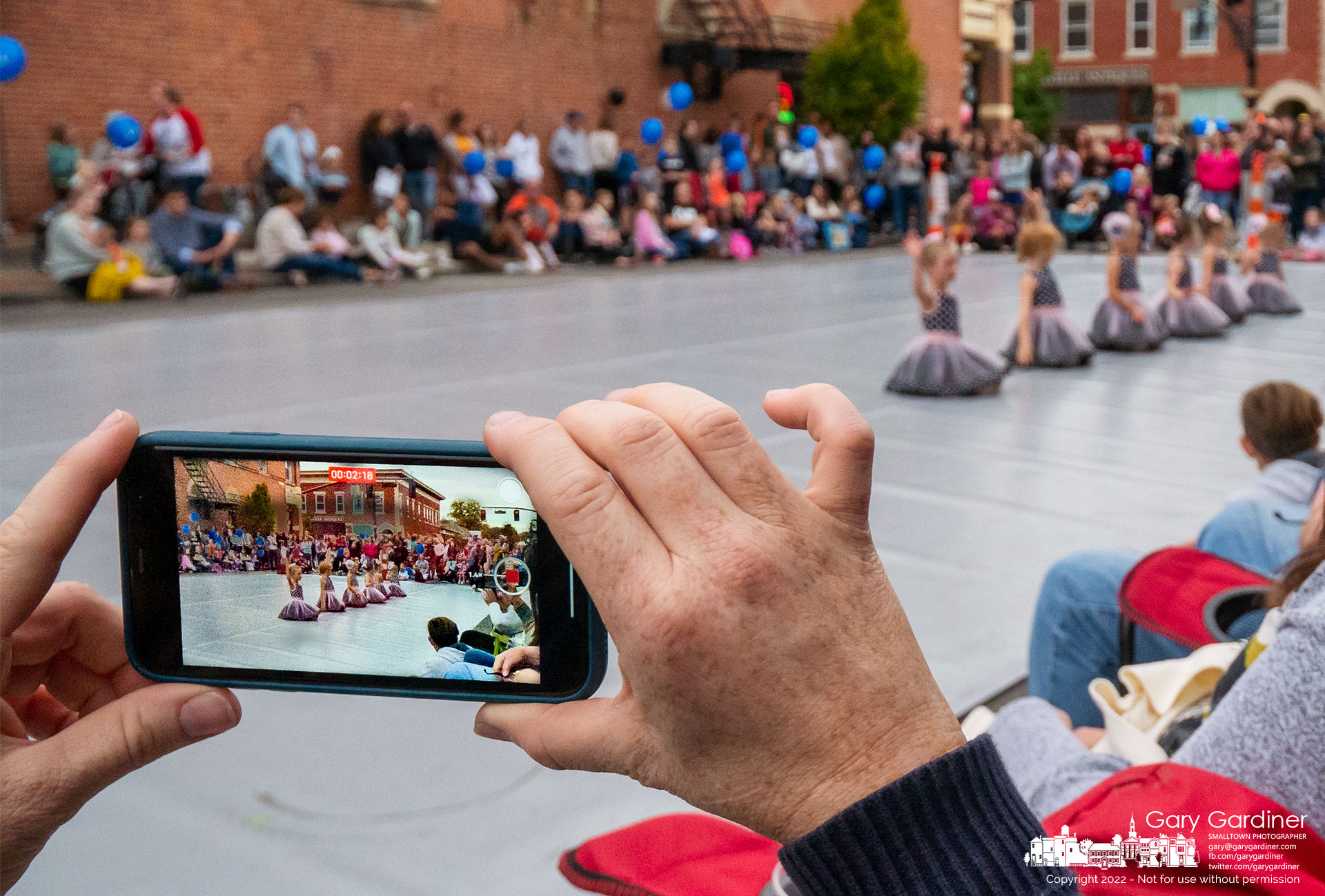A mother uses her phone to record video of her daughter as part of Generations dancers performing on West College during Fourth Friday. My Final Photo for September 23, 2022.