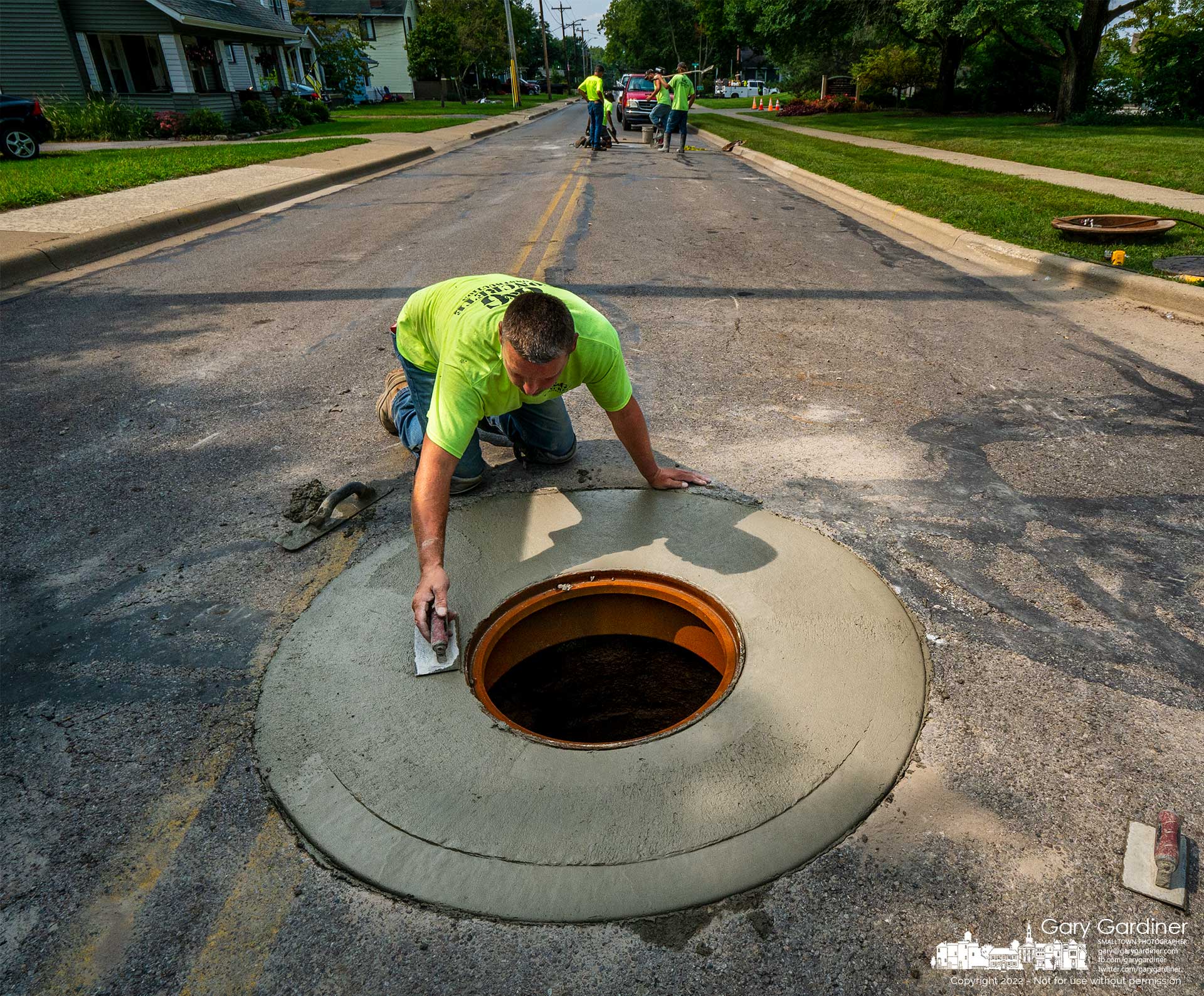 A worker smooths the edges of new concrete poured around a manhole after repairs to several manholes on East Walnut near State Street. My Final Photo for Sept. 16, 2022.