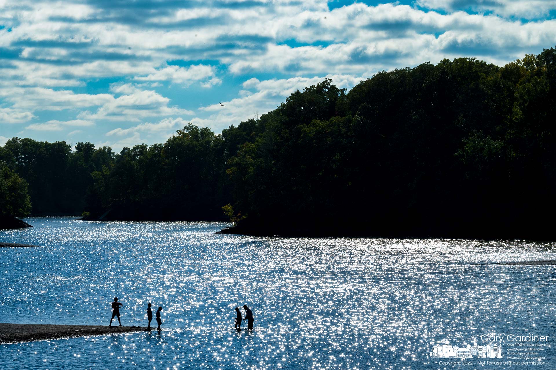 A family retrieves objects from the shallows at the Twin Bridges boat landing as the afternoon sun reflects in ripples formed by wind at Hoover Reservoir. My Final Photo for October 2, 2022.