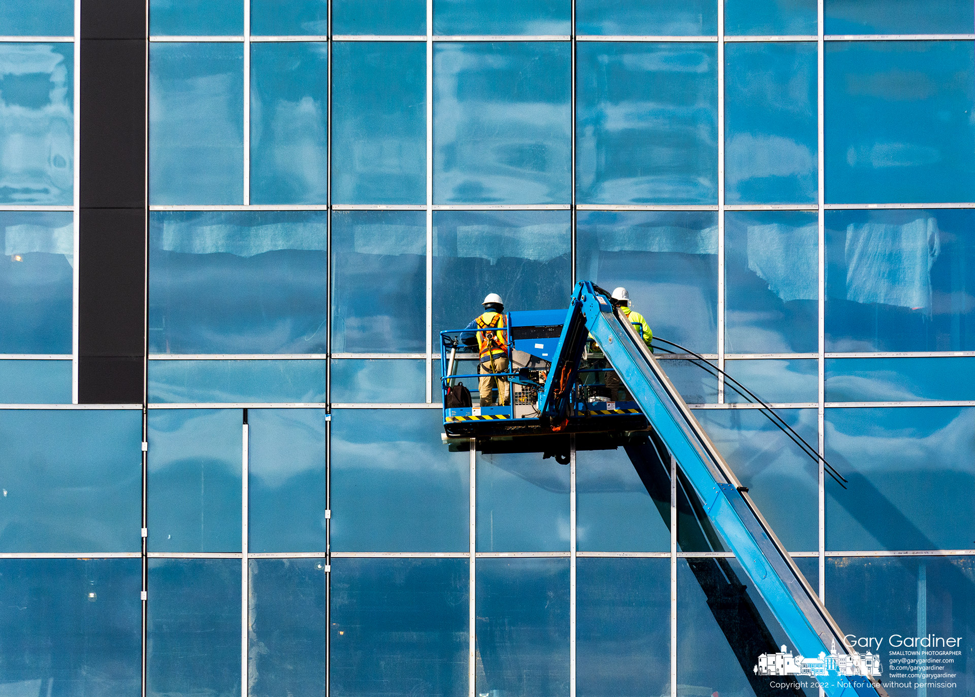 A bright, cloudy sky is reflected in the windows as workmen install seals around the windows of the Ortho One building being built at Africa Road and Polaris Parkway. My final Photo for November 1, 2022.