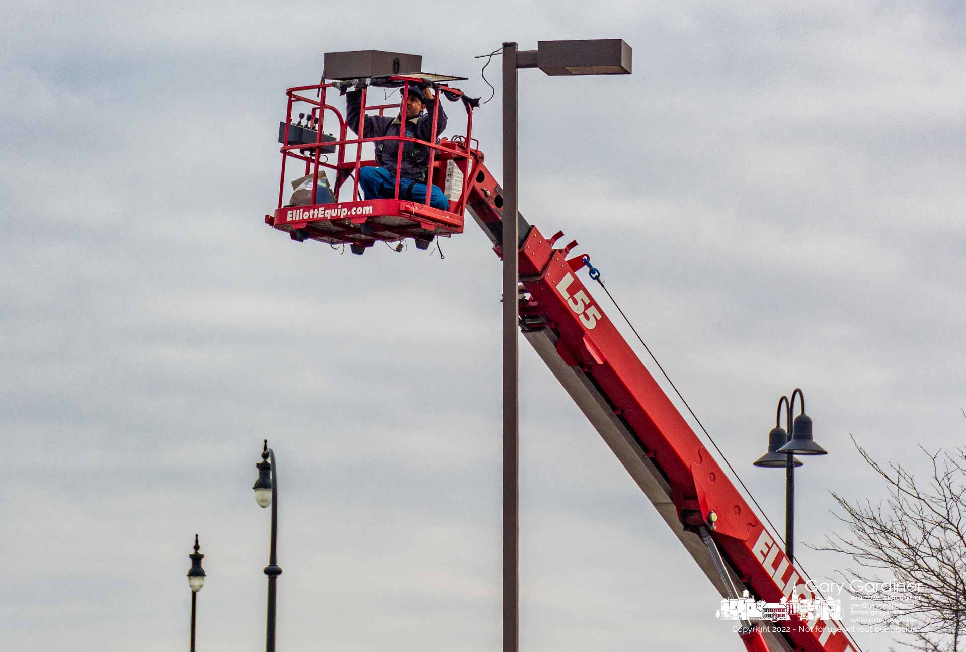 An electrician removes a sodium vapor light fixture at the Westerville Center shopping center to replace it with new LED fixtures. My Final Photo for November 29, 2022. 
