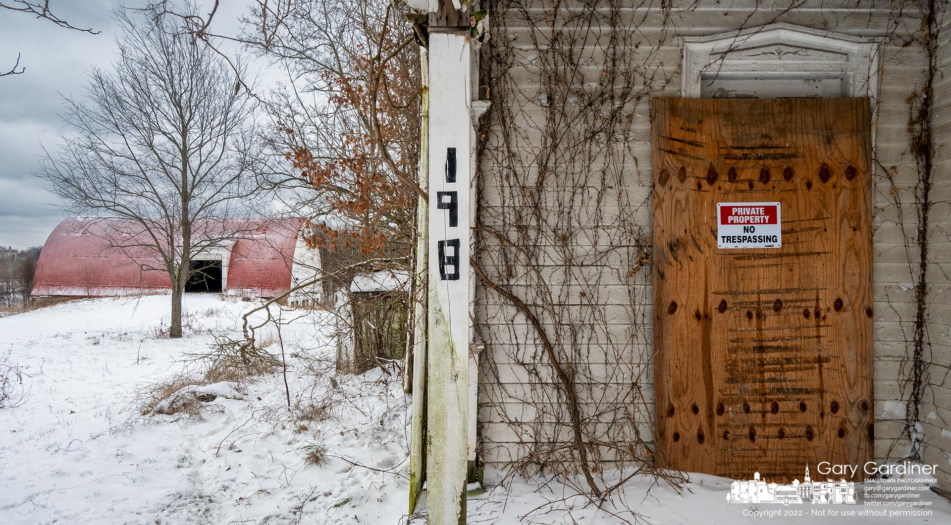 One of several new "No Trespassing" signs hangs on the plywood covering the door of the old farmhouse at the Braun Farm where developers hope to demolish the house and barn as part of plans to feel the property. My Final Photo for December 26, 2022.
