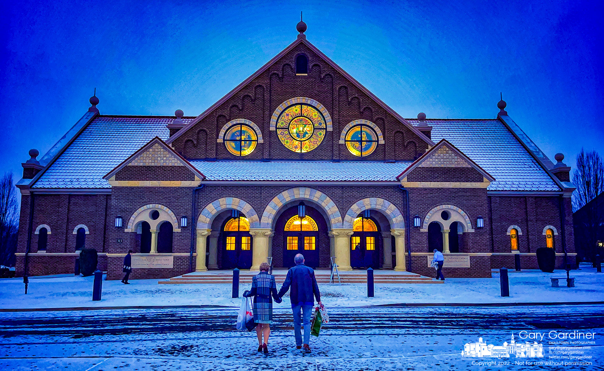 A couple carries donations into St. Paul the Apostle Catholic Church before sunrise on a below-freezing morning with an overnight dusting of snow. My Final Photo for December 18, 2022.