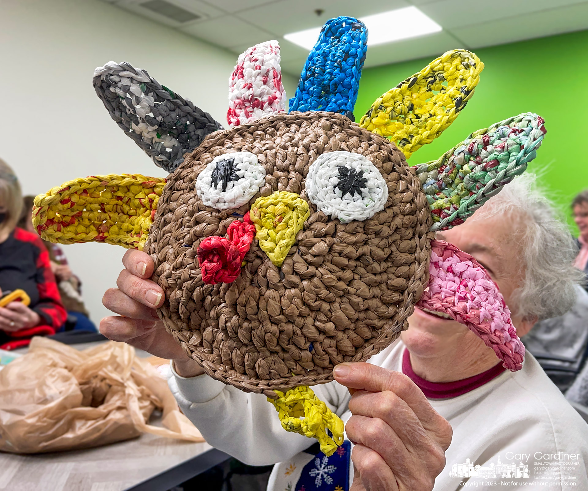 A knitter at a Westerville Libary club meeting shows off the turkey she made using plastic shopping bags in a technique named plarning, a combination of plastic and yarn using plastic strips instead of traditional yarn to make a bag, or in this case a Plarn turkey, that can be easily washed without damage, shrinkage, or losing its shape. My Final Photo for January 5, 2023.
