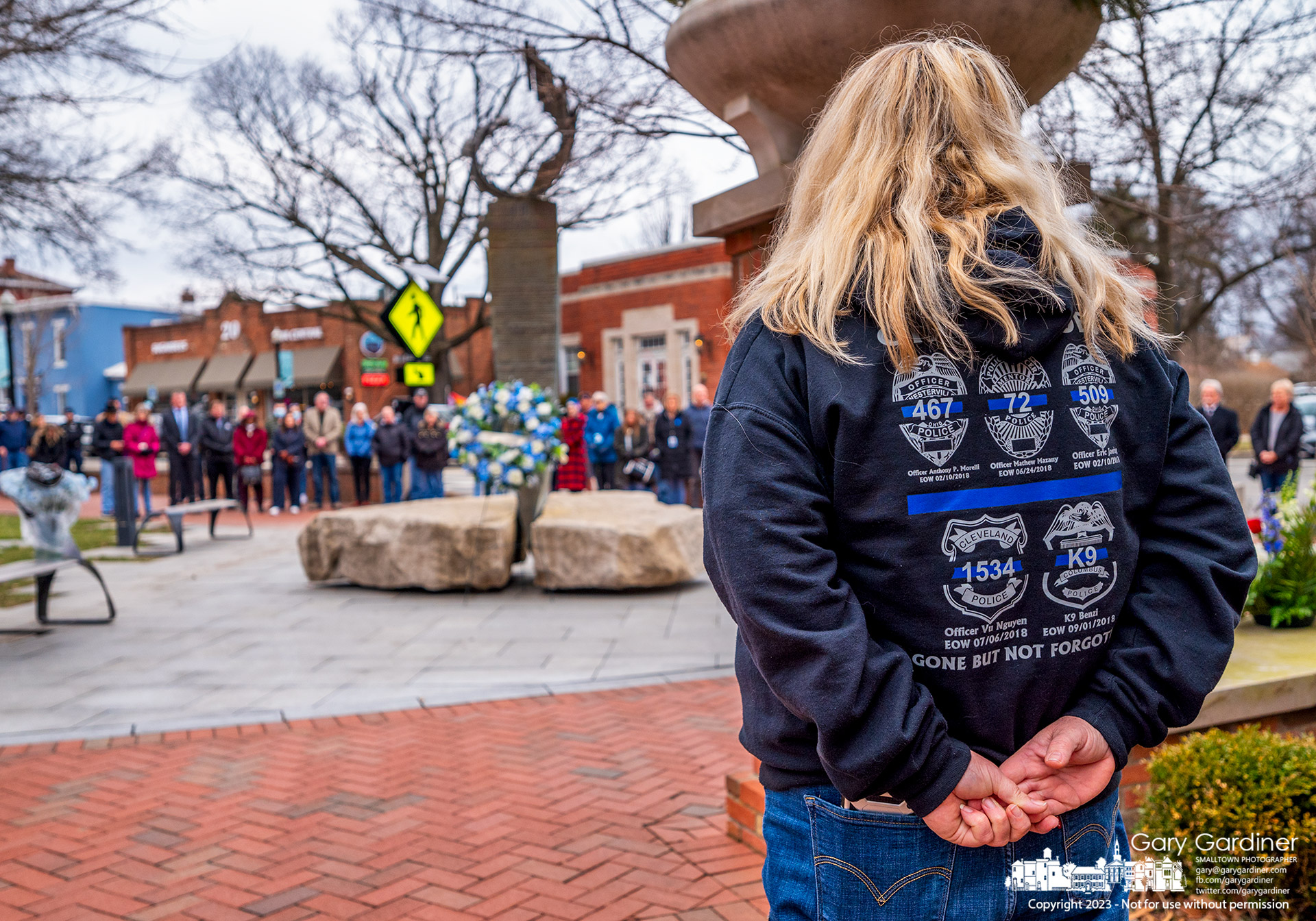 A woman wears a jacket bearing patches marking the names of police officers killed in the line of duty including Westerville officers Moretti and Joering at a wreath-laying ceremony at city hall on the fifth anniversary of their deaths. My Final Photo for February 10, 2023.