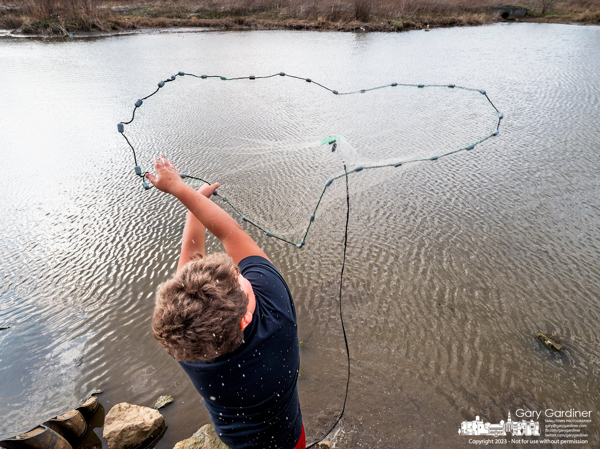 A young fisherman casts his net in the shallow waters of the wetlands at Highlands in search of bait fish for a later trip for a larger catch. My Final Photo for April 4, 2023.