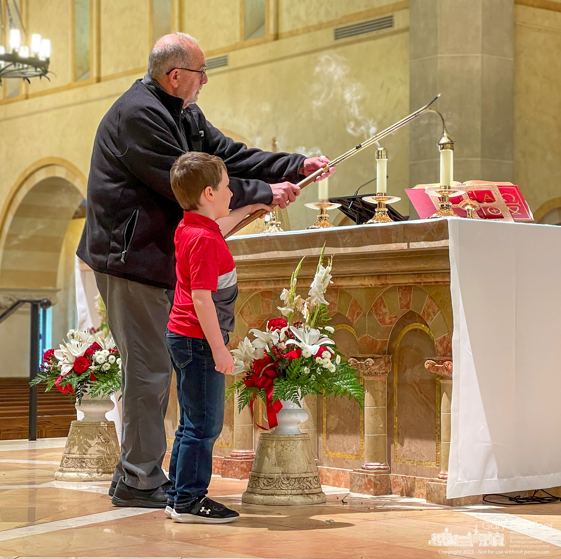 An usher at St. Paul the Apostle Catholic Church gets an assist extinguishing candles on the altar after the early Sunday Mass. My Final Photo for April 30, 2023.