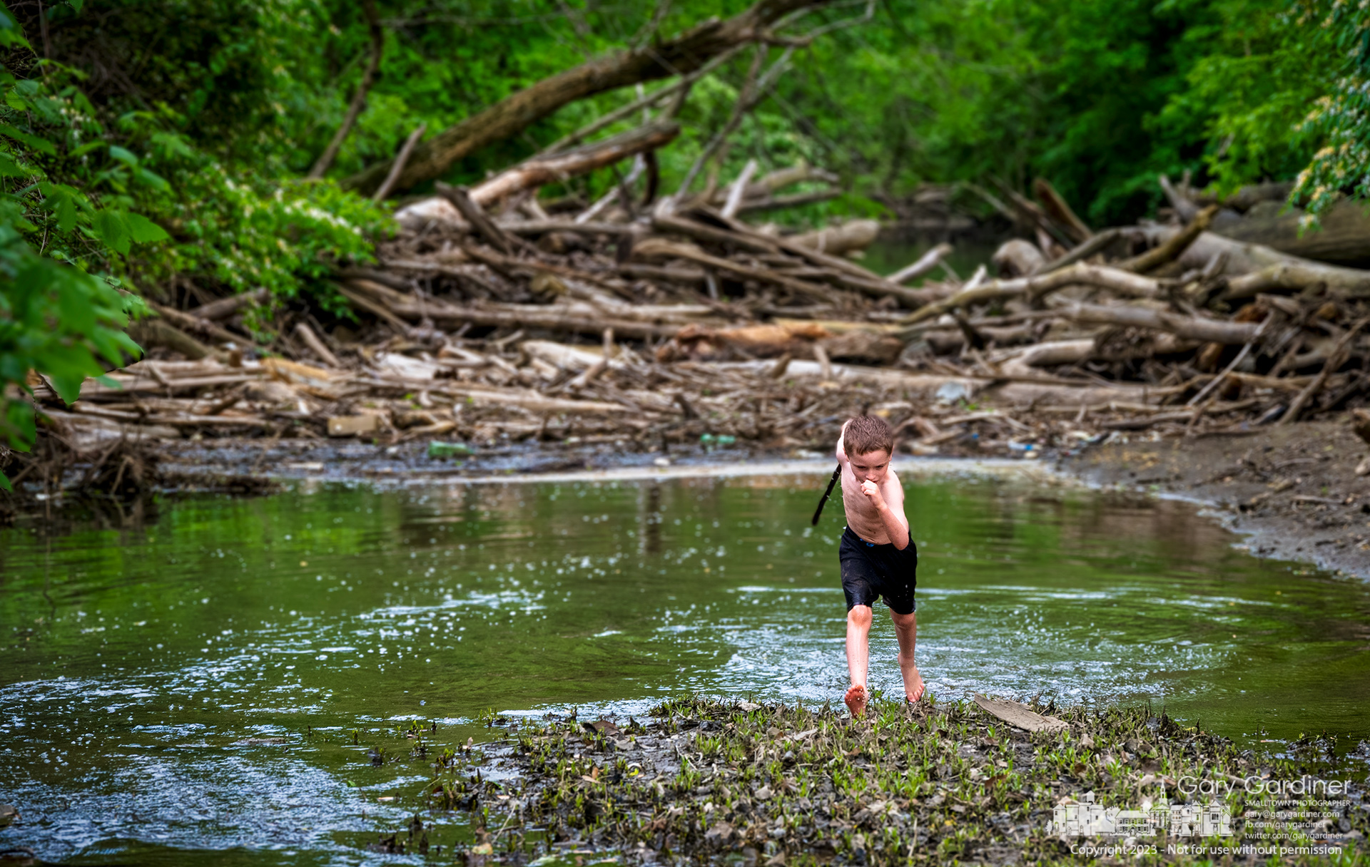 A young boy strides upstream as he battles imaginary enemies in the shallow waters of Alum Creek just below the low-head dam in Westerville. My Final Photo for May 14, 2023.
