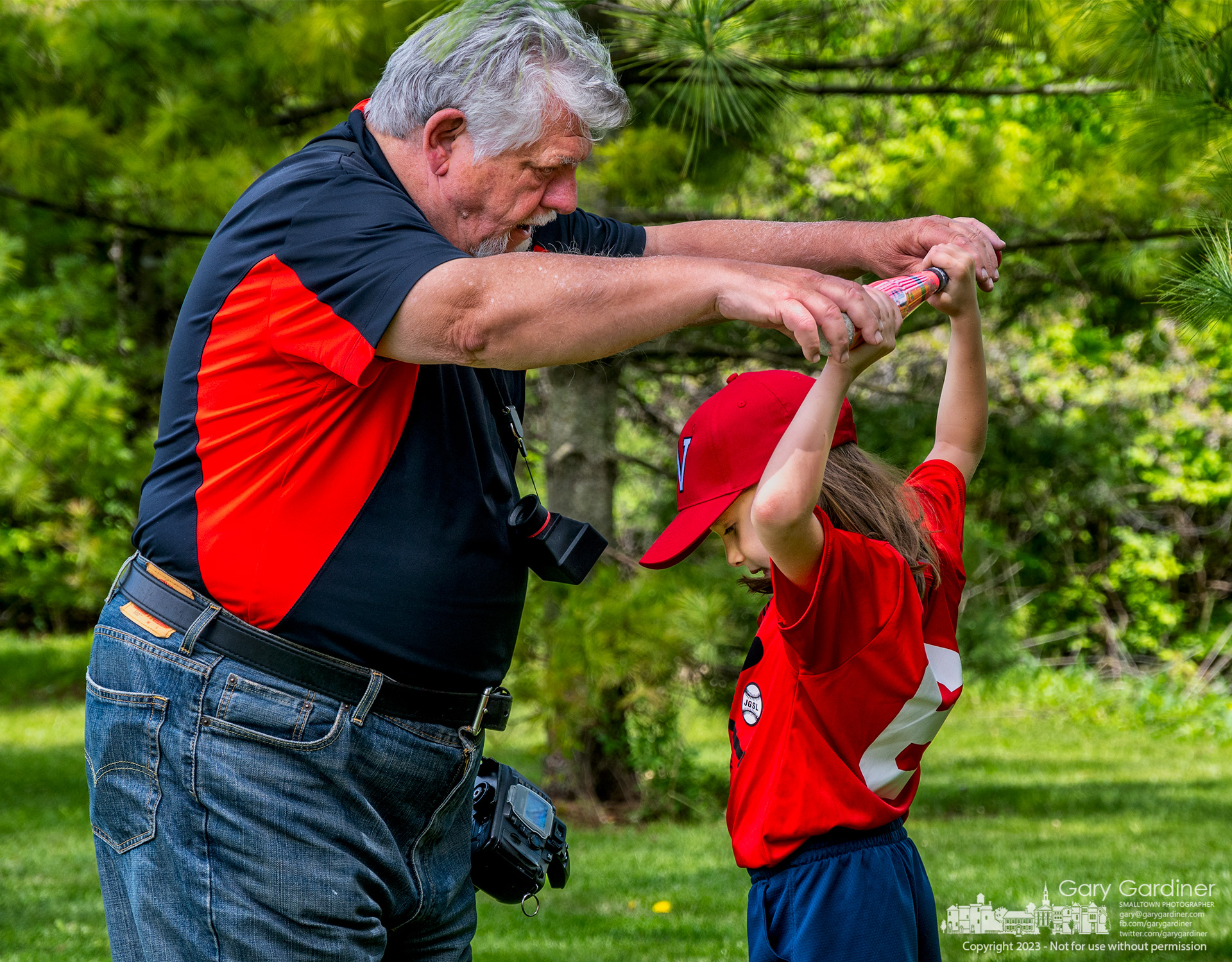 Sports photographer Gil Balden helps a WYBSL player get her bat into position on her shoulders during team and individual photoshoots at Huber Village Park Saturday. My Final Photo for May 6, 2023.