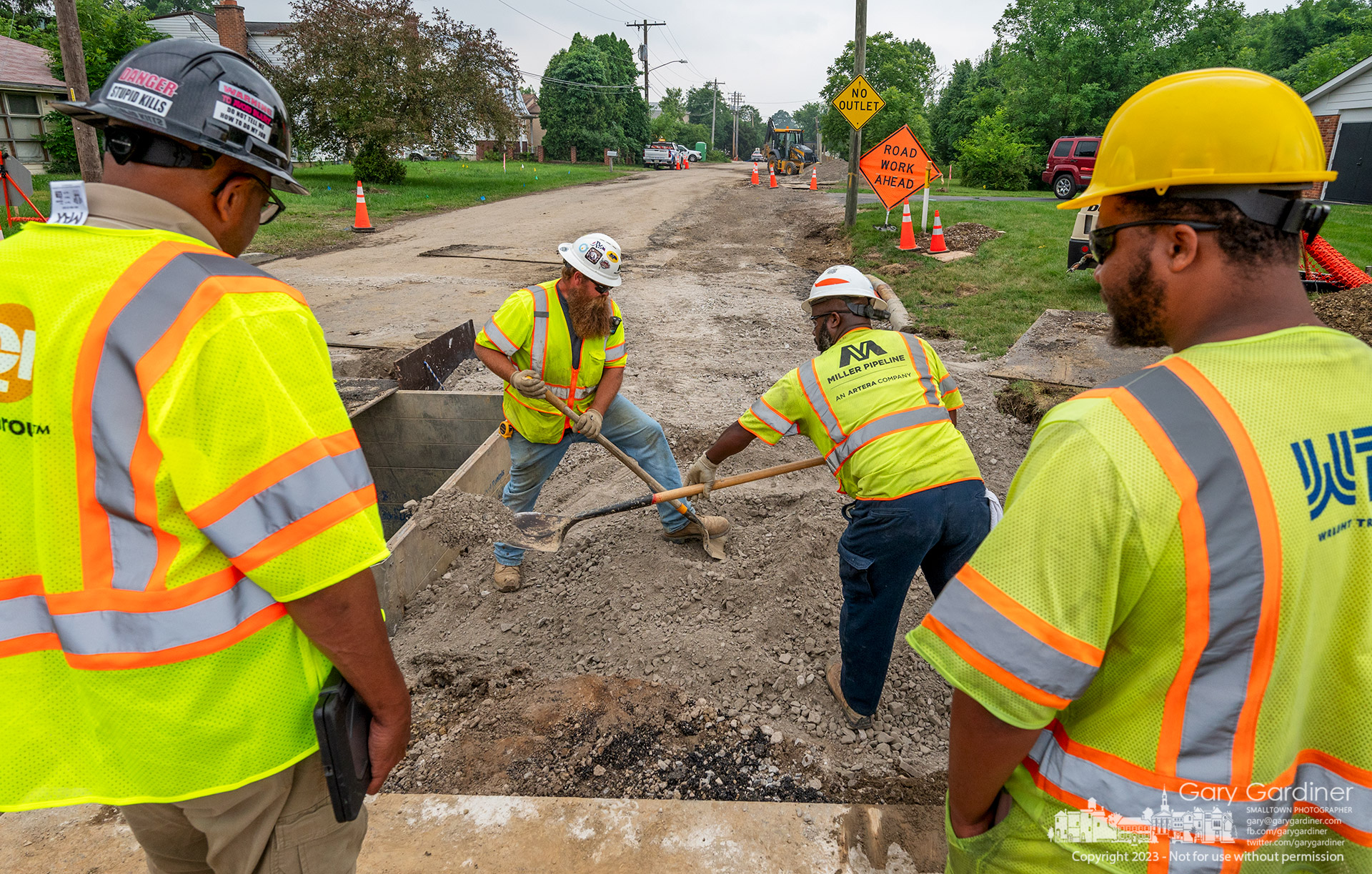 A pair of pipeline installers under the watchful of an inspector and safety crew member shovel fill into a hole where a new gas line was laid adjacent to a new water line connecting to East Broad Street in Westerville before the road is rebuilt with curbs and a new surface. My Final Photo for June 27, 2023.