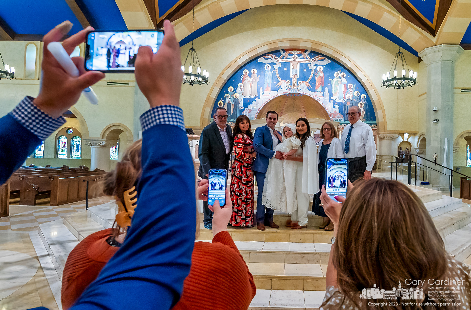Family and friends raise their phone cameras to take photos recording a child's Rite of Baptism at St. Paul the Apostle Catholic Church in Westerville. My Final Photo for June 25, 2023.