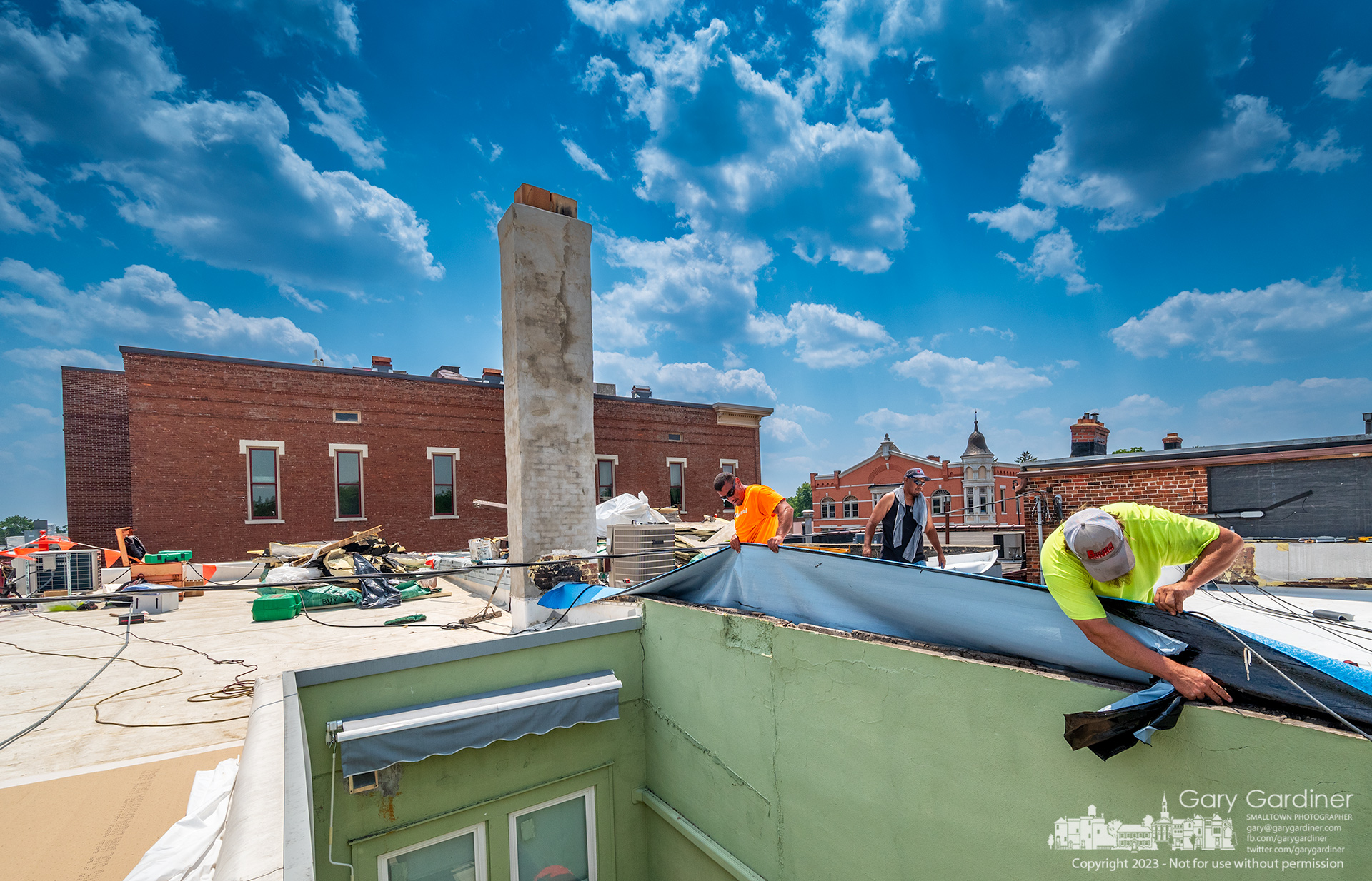 Workers replace the roof bladder on the top of the building on East College that houses Cardinal Pizza and Grandfather Clock Company. Across the streets are Old Bag o' Nails and the Holmes Hotel. My Final Photo for June 9, 2023.