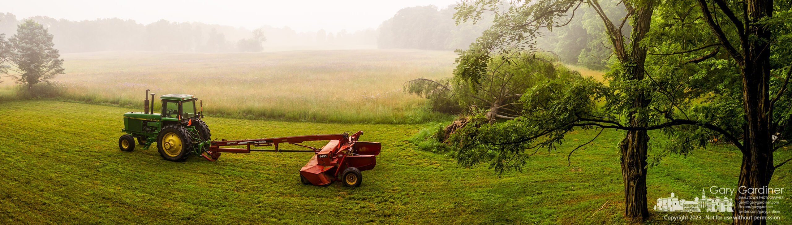 Morning haze and fog obscures the hay field at the Sharp Farm where the farmer has placed his tractor to begin cutting hay later in the day. My Final Photo for June 28, 2023.