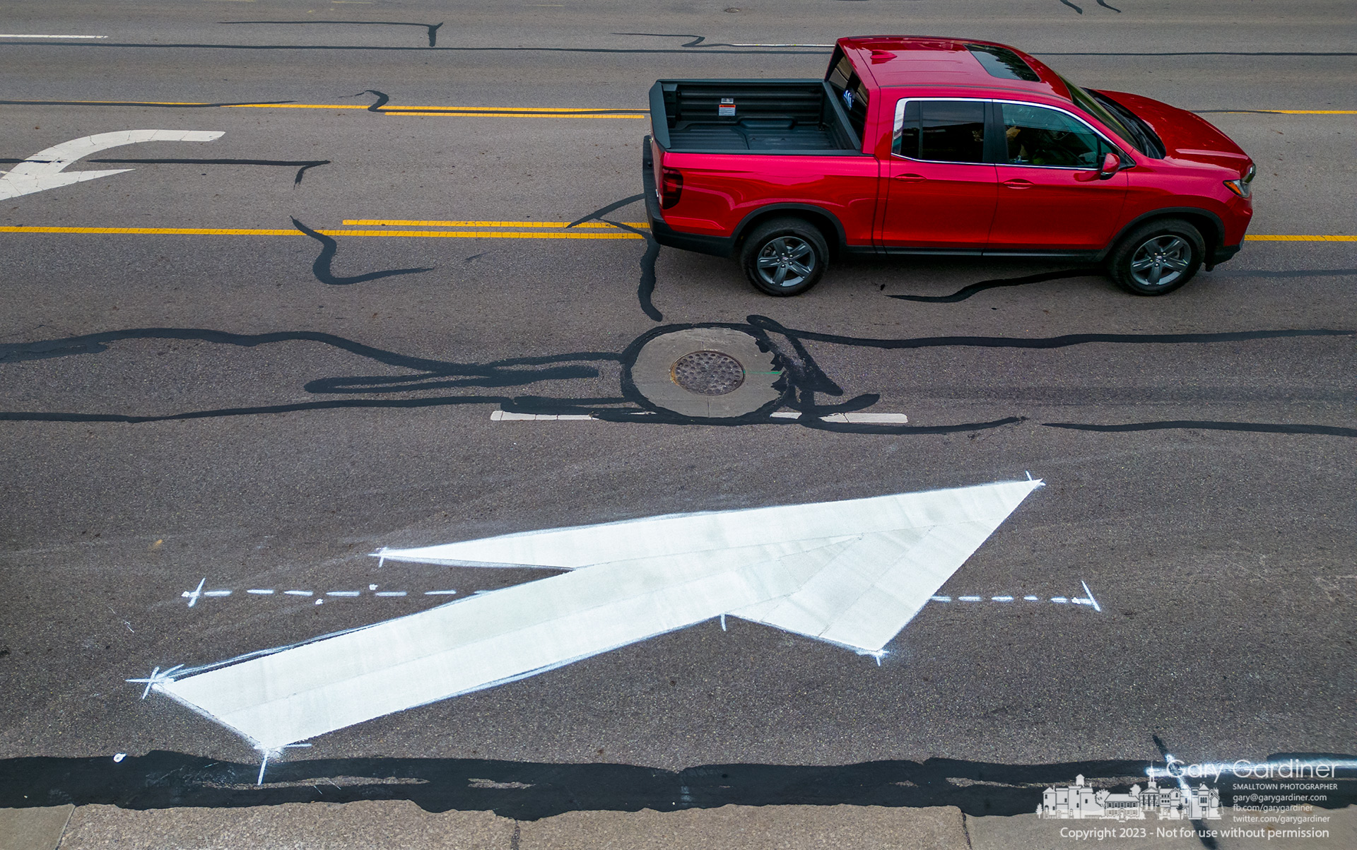 A truck drives past a freshly painted lane change arrow on South State Street where the curb lane is changed to parking near a new apartment complex, coHatch, and a brewery. My Final Photo for June 19, 2023.
