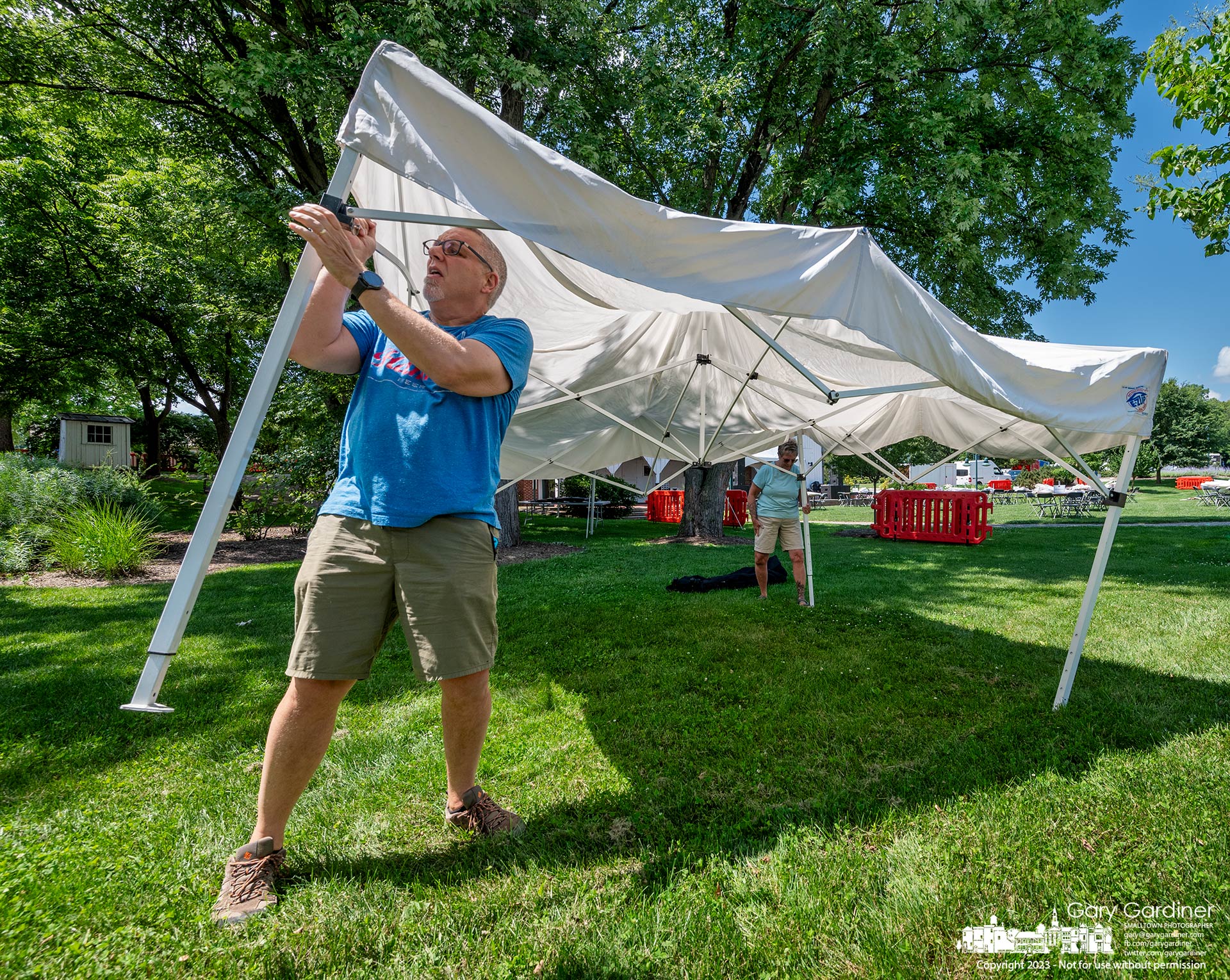 An artist's helper gives extra pressure to secure a popup tent pole as he and others set up spaces in Heritage Park for the weekend's Westerville Music and Arts Festival. My Final Photo for July 7, 2023.