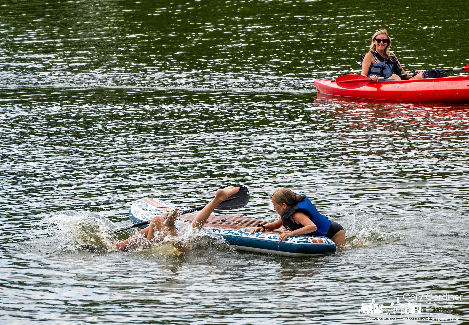 A trio of young girls take turns being the queen of the paddleboard before tossed into the waters of Hoover Reservoir near the Oxbow boat ramp. My Final Photo for July 23, 2023.