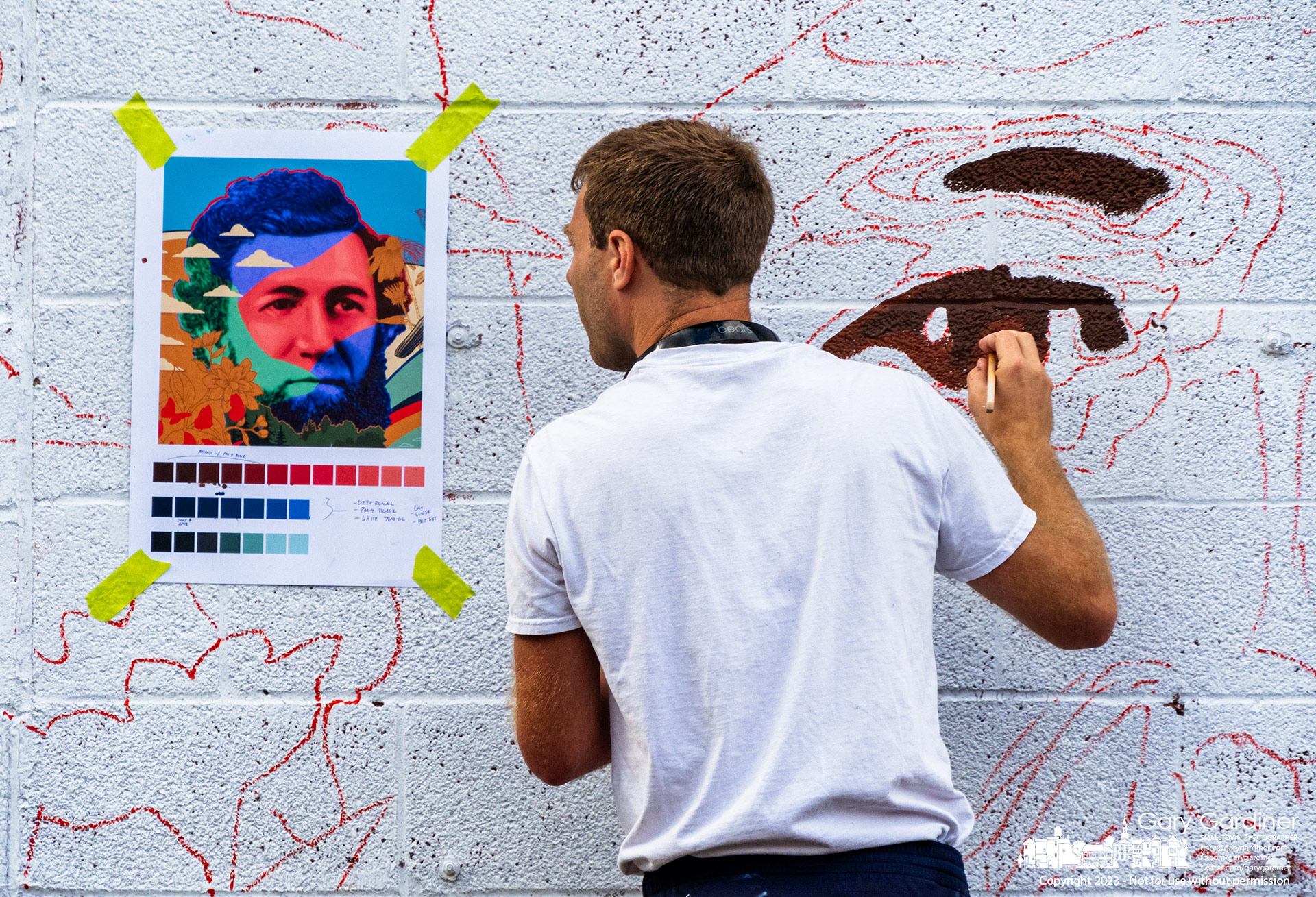 Muralist Nick Stull references his original artwork as he makes the beginning strokes for the historical mural featuring Benjamin Hanby, William Henry Fouse, and Agnes Meyer Driscoll, on the side of the building that houses Java Central. My Final Photo for August 15, 2023.