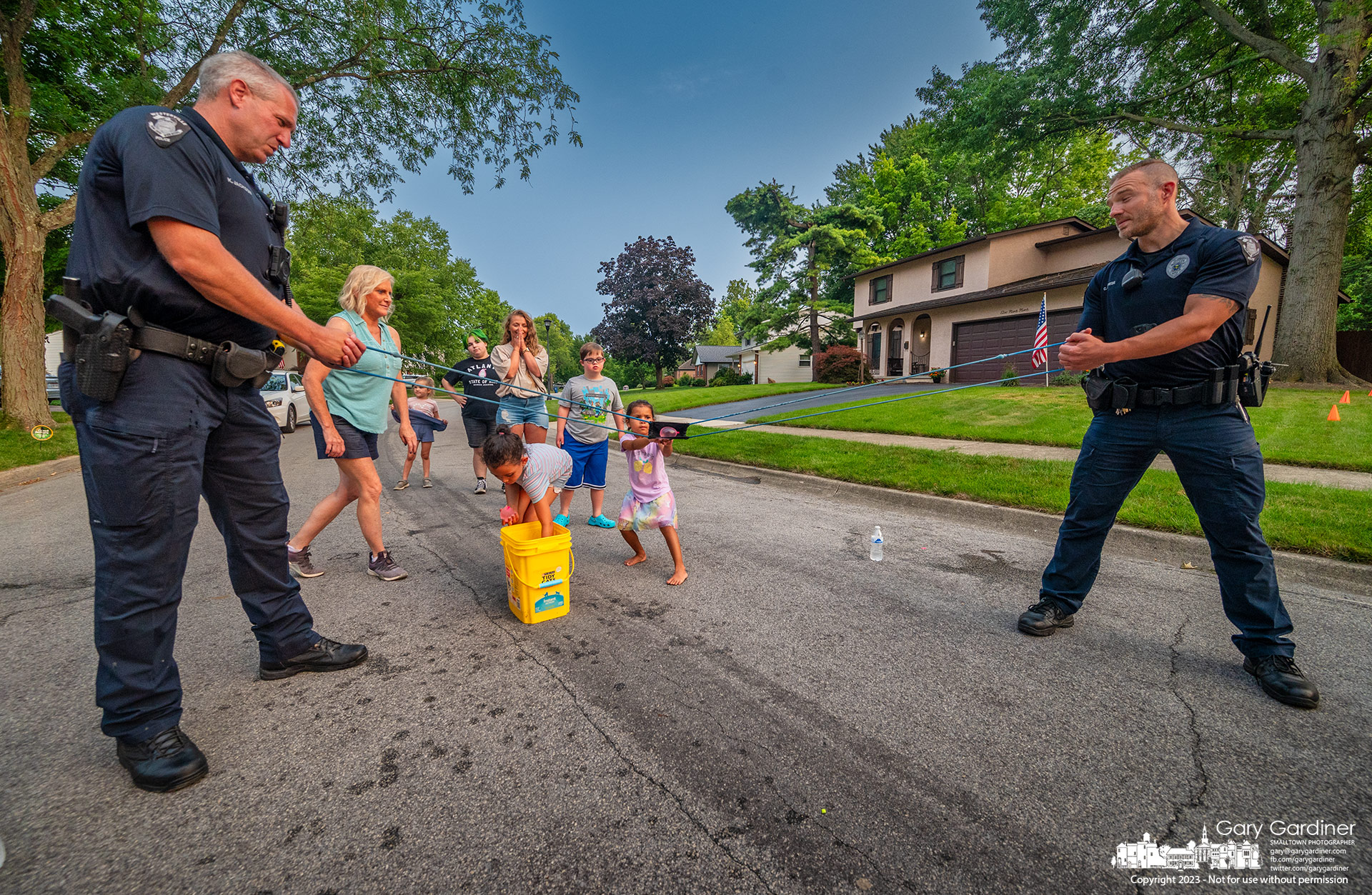Westerville police officers assist a group of kids using a water balloon slingshot against other kids and a few adults at National Night Out. My Final Photo for August 1, 2023.