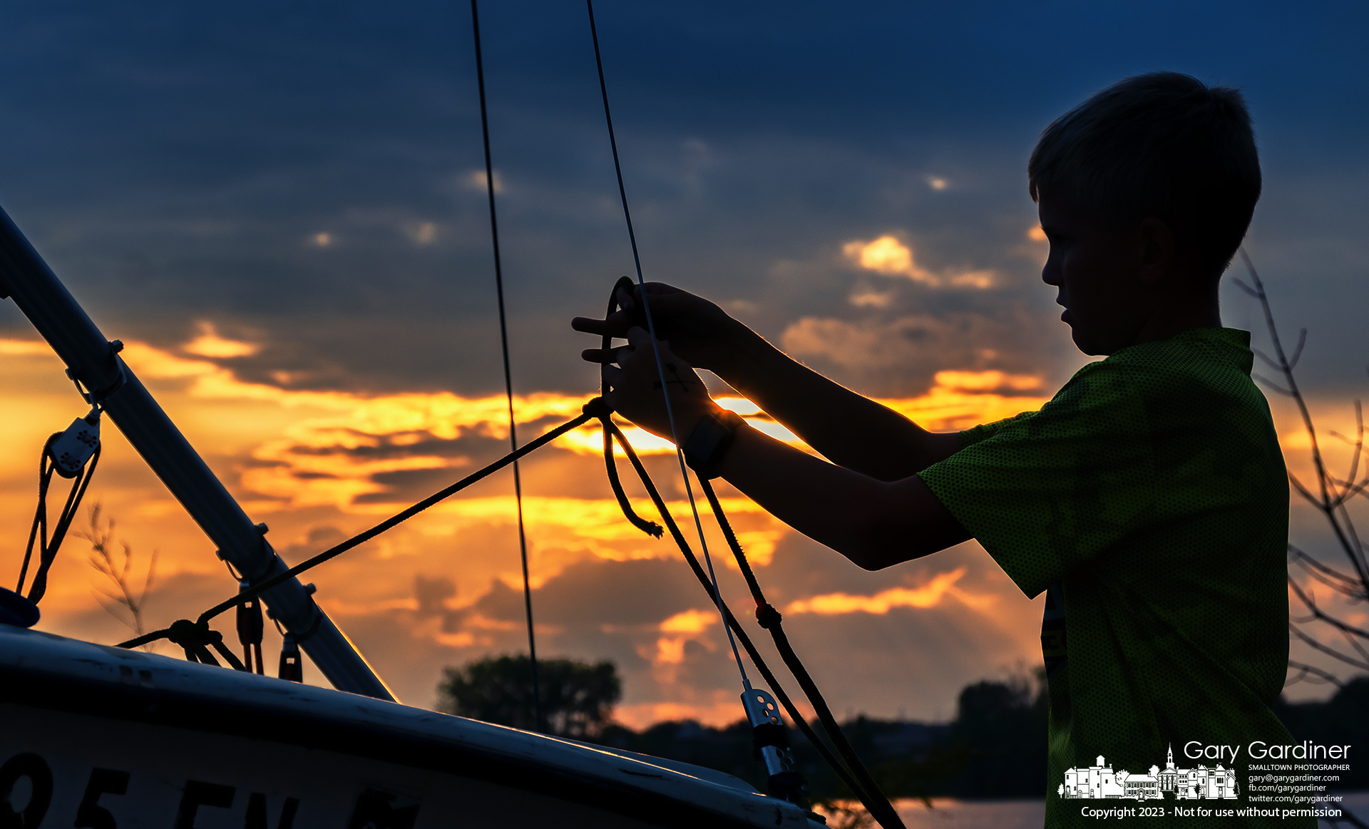 A young sailor ties of the lines on his boat after finishing training races at Hoover Reservoir Thursday at sunset. My Final Photo for September 7, 2023.