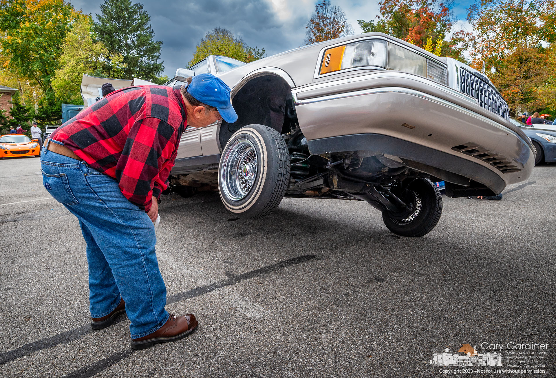 A man studies the undercarriage of an airlfted lowrider at the Columbus Cars and Coffee car show at the parking lot at city hall in Westerville. My Final Photo for October 7, 2023.