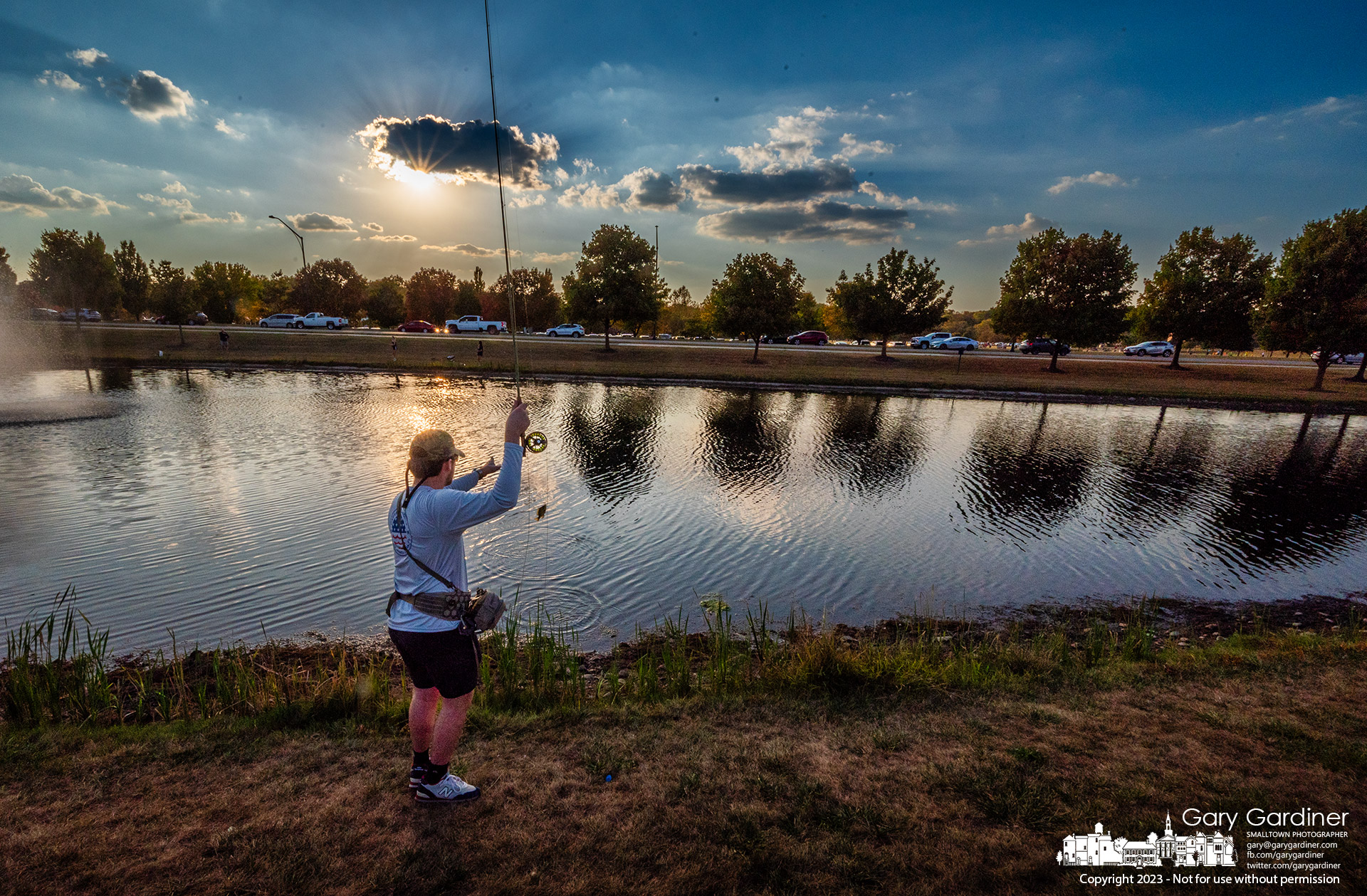 A fly fisherman retrieves a small fish from the community center holding pond where late afternoon fishing is popular. My Final Photo for October 3, 2023.