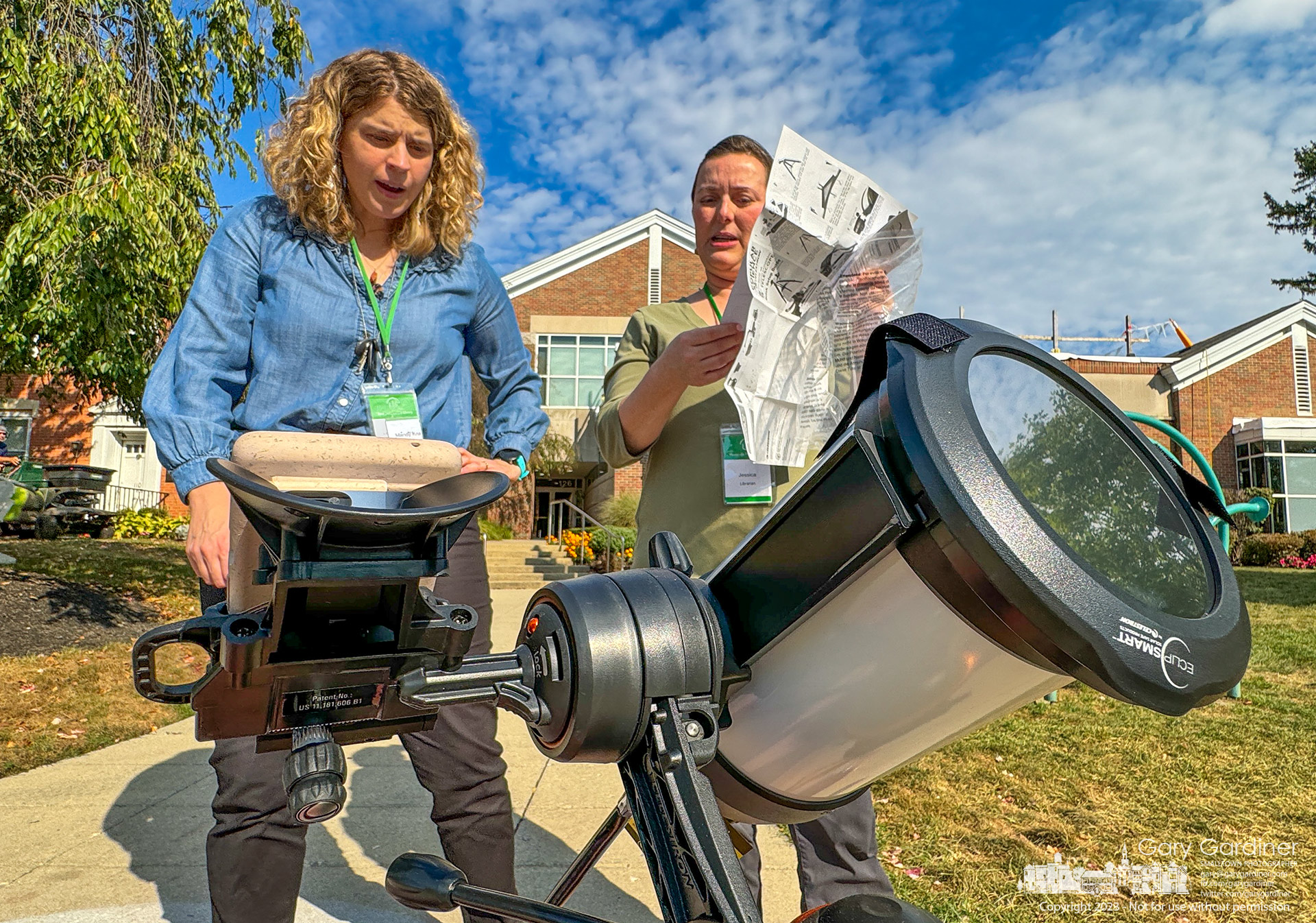 Librarians read the instructions for setting up the Westerville Library's new telescope with an eclipse filter as it prepares for Saturday's partial annular eclipse. My Final Photo for October 12, 2023.