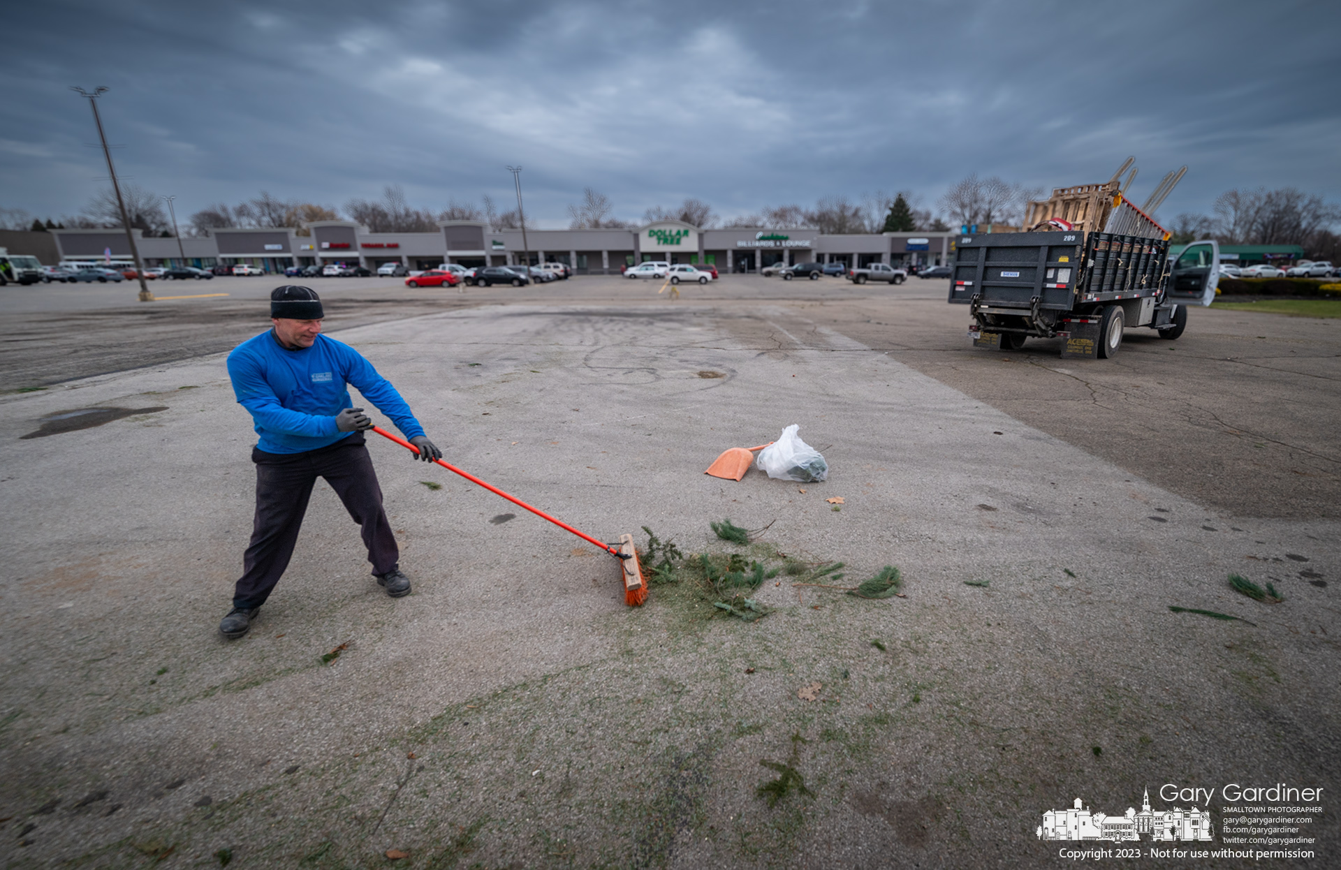 Limbs and needles are swept away as the last act of cleanup at the Christmas tree lot at Glengary Shopping Center in Blendon Township as it shuts down for the season. My Final Photo for December 22, 2023.