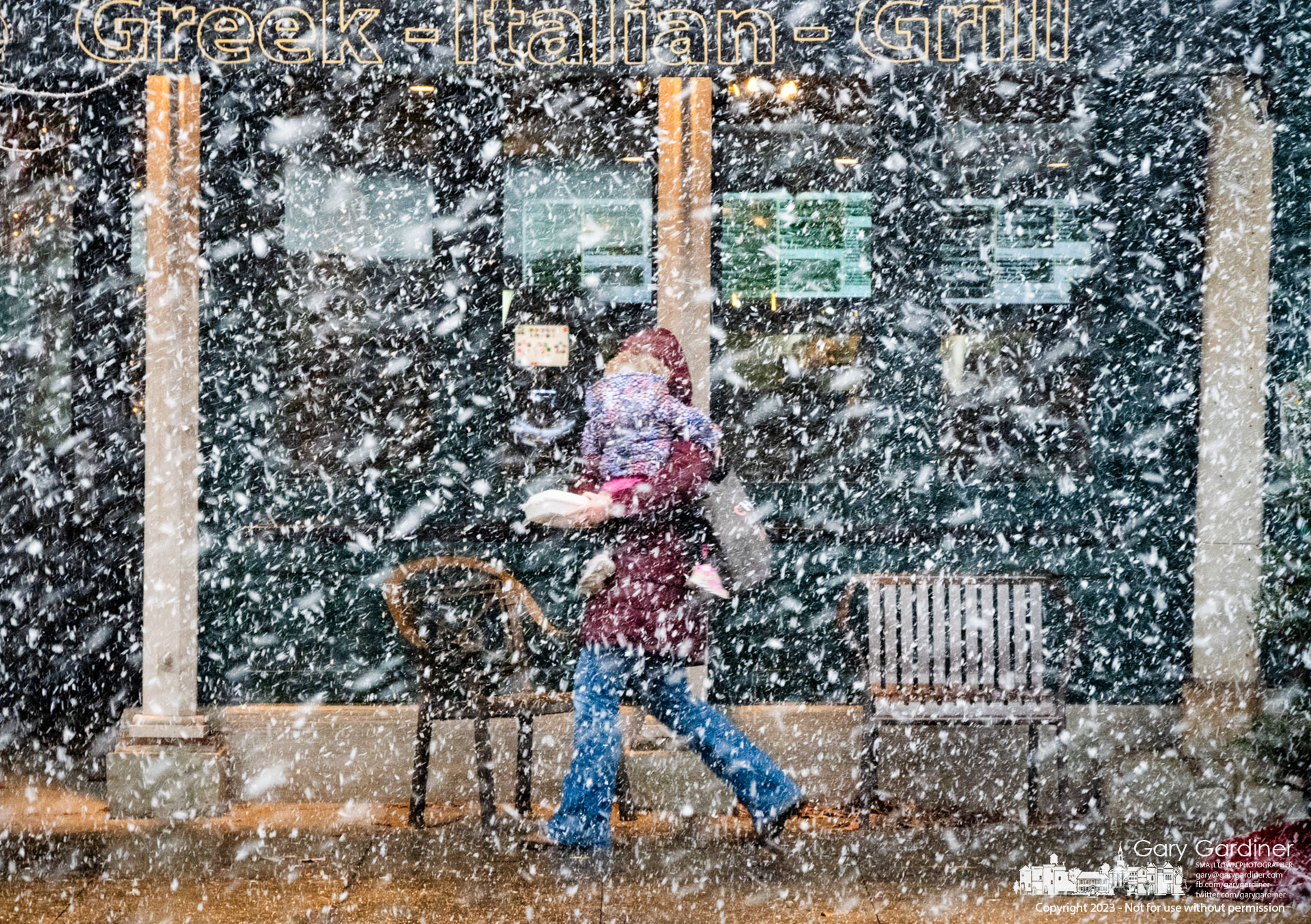 Woman and child walk through a thick snow squall after leaving Koble Grill with leftovers Monday afternoon. My Final Photo for December 18, 2023.