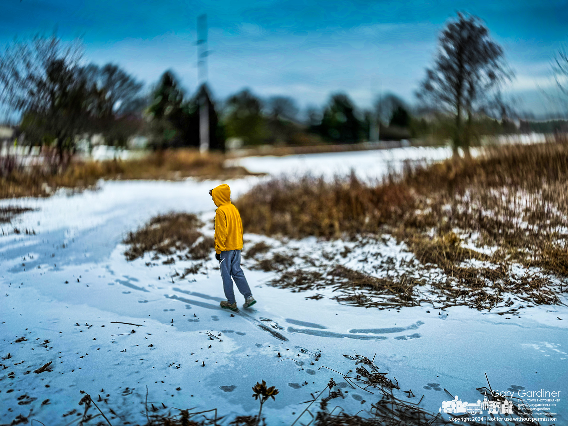 A young boy traces his steps across the frozen wetlands at Highland Park as daytime temperatures never go above freezing. My Final Photo for January 18, 2024.