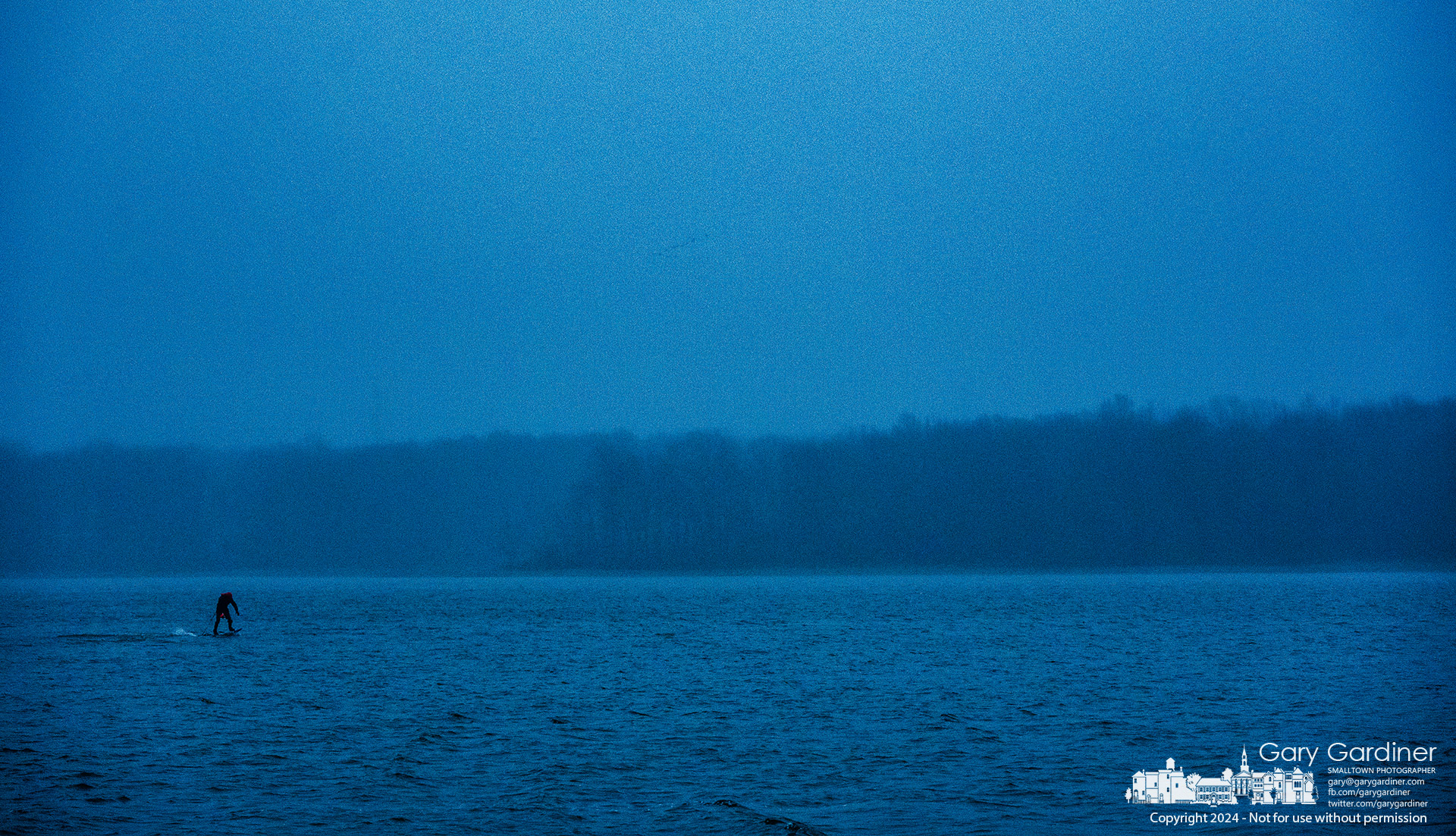 An e-foil boarder runs into the rain and wind towards the dam at Hoover Reservoir after changing to the e-foil after the wind for his sailboard died. My Final Photo for January 9, 2024.