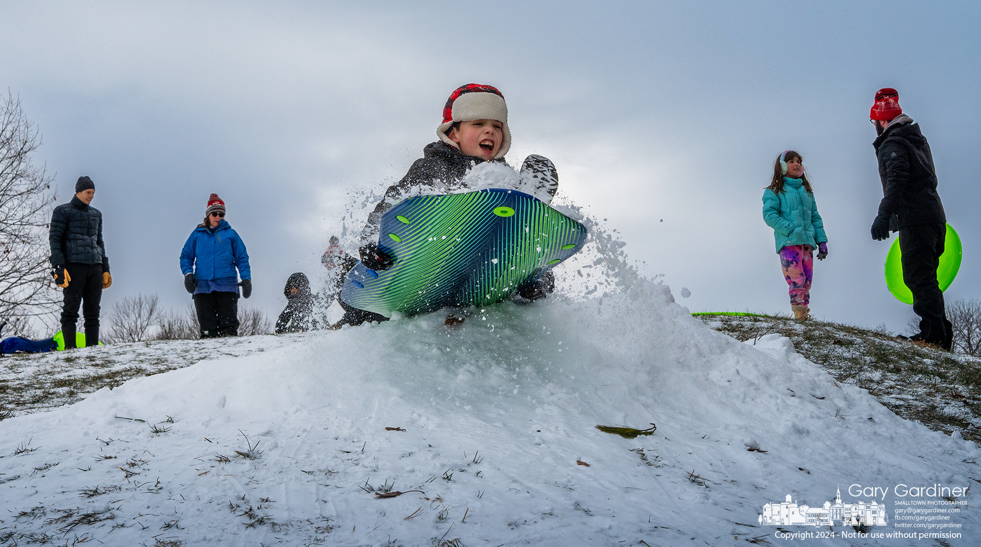 A youngster rides his sled over a snow ramp he and his friends built to add to the excitement of sledding at the small hill by the wetlands at Highlands Park. My Final Photo for January 20, 2024.