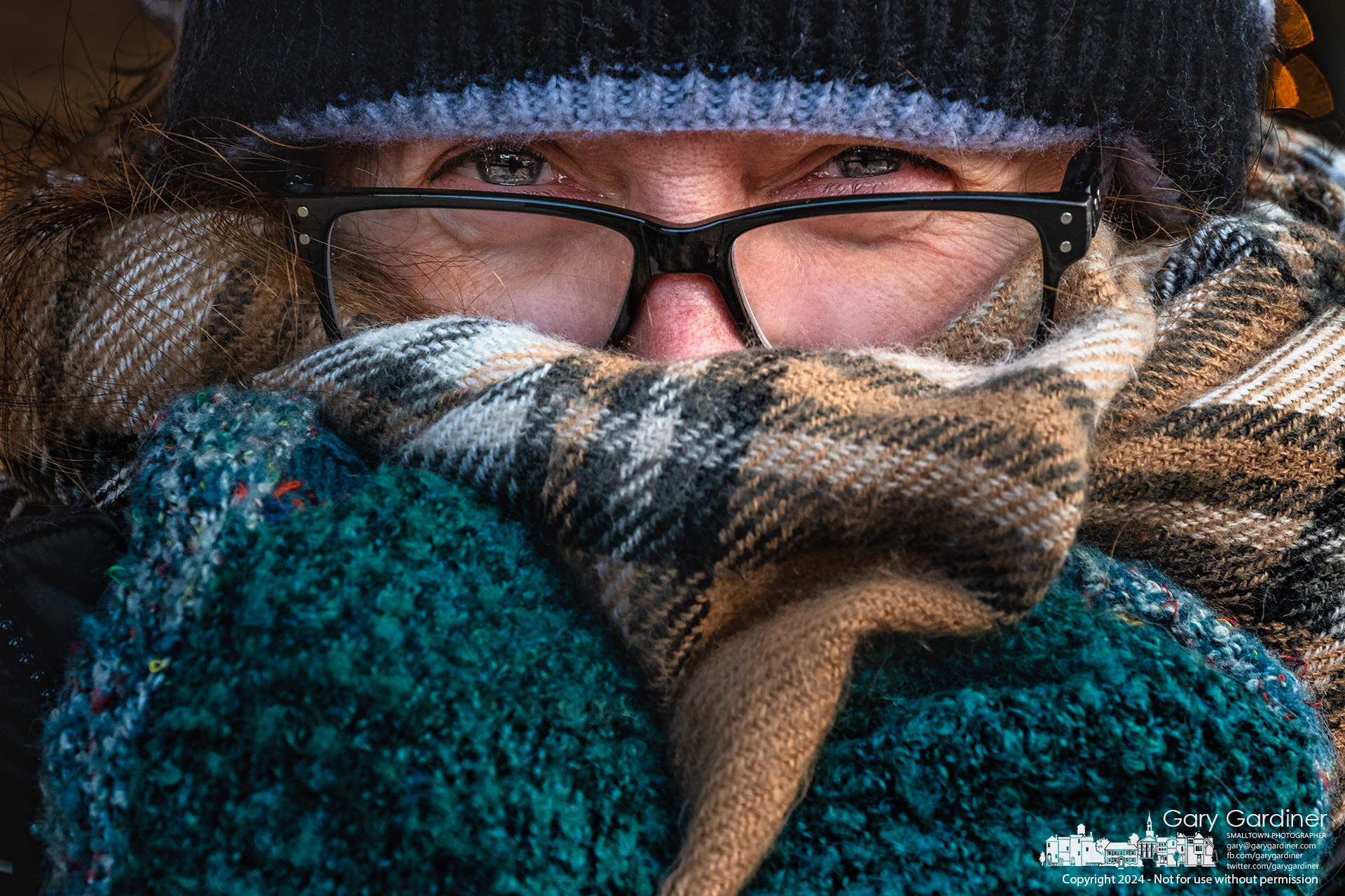 A shopper uses her mittened hands to hold a woolen scarf over her face as she exits a store in Uptown Westerville on a windy and cold winter afternoon. My Final Photo for January 17, 2024.
