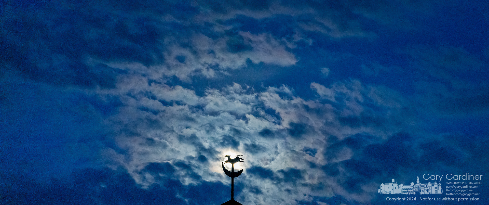 The full moon shines through a cloud layer as it rises behind the bovine and lunar weather vane atop Children's Hospital in Westerville. My Final Photo for February 23, 2024.