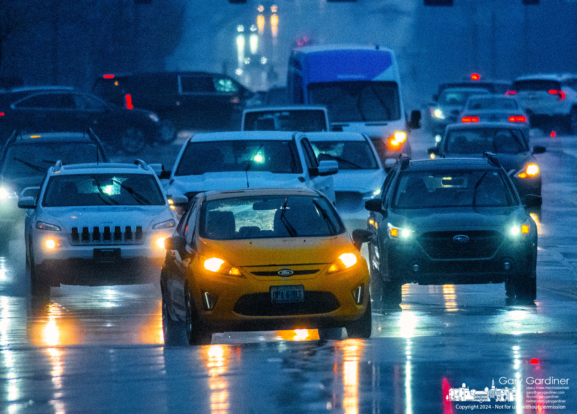 A caravan of vehicles crosses Otterbein Avenue as they travel east on Schrock Road in a rainstorm about 15 minutes after sunset Thursday. My Final Photo for February 22, 2024.