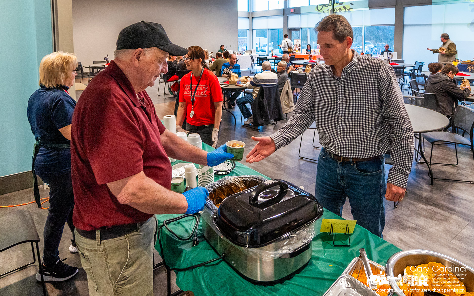 A man is served homemade chicken tortilla soup by the chef at Souperbowl Dinner to raise money for W.A.R.M. at the Senior Center in the Community Center. My Final Photo for February 8, 2023.