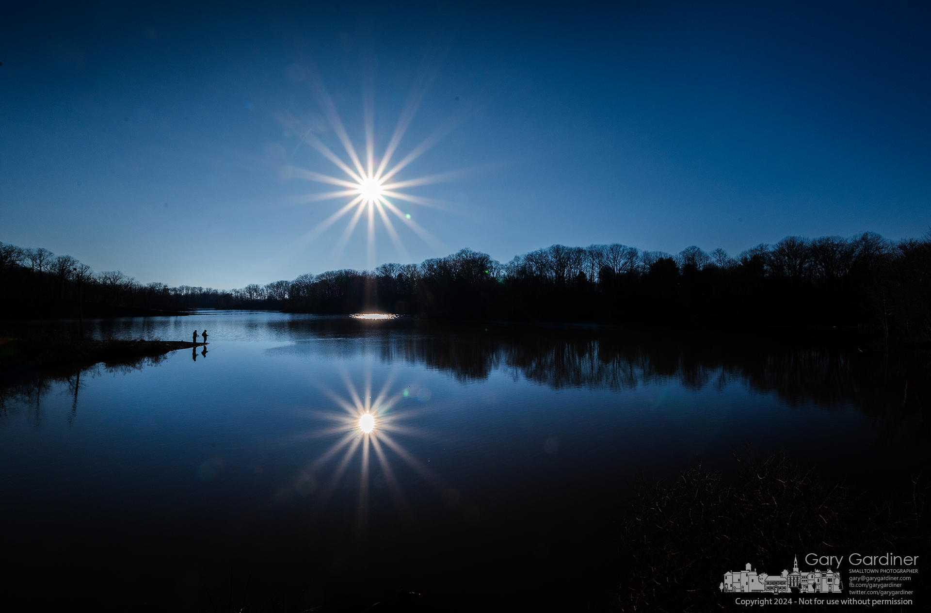 Two fishermen stand at the edge of Hoover Reservoir Saturday with the afternoon sun reflected in the high waters of the lake. My Final Photo for February 3, 2024.