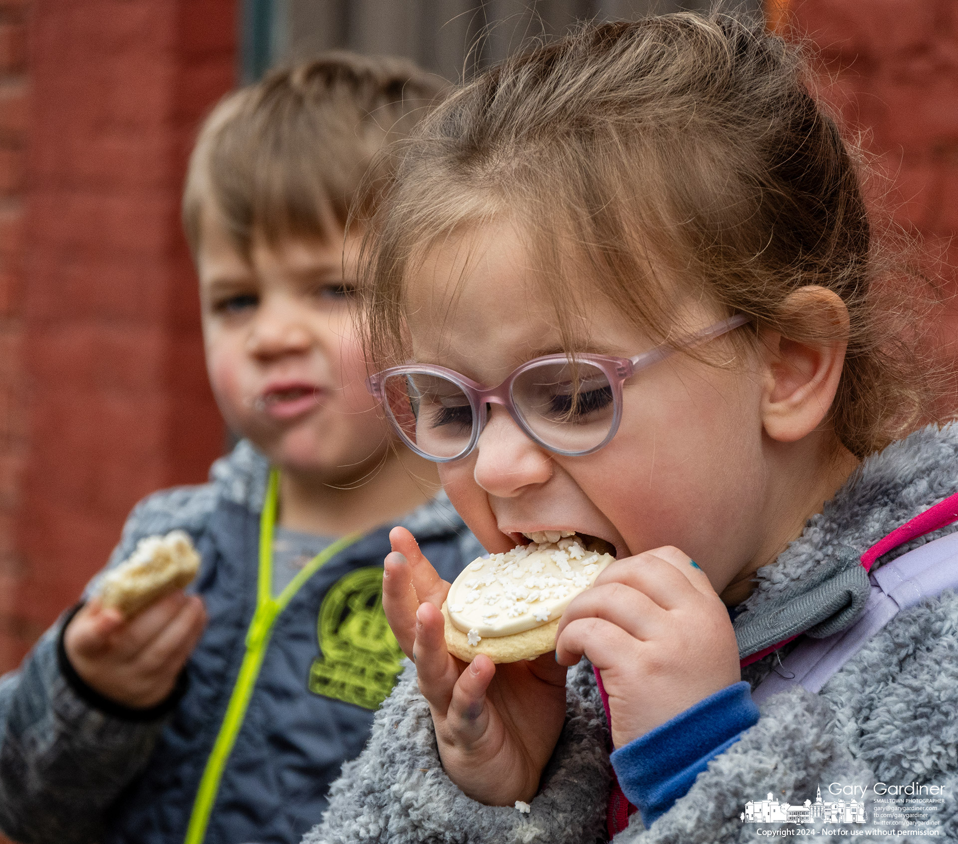 Six-year-old Lucy Todd bites into a cookie as her brother, Mike, 3, chews on the cookie his parents got for them at the Cookie Walk in Uptown Westerville Saturday afternoon. My Final Photo for February 2, 2024.