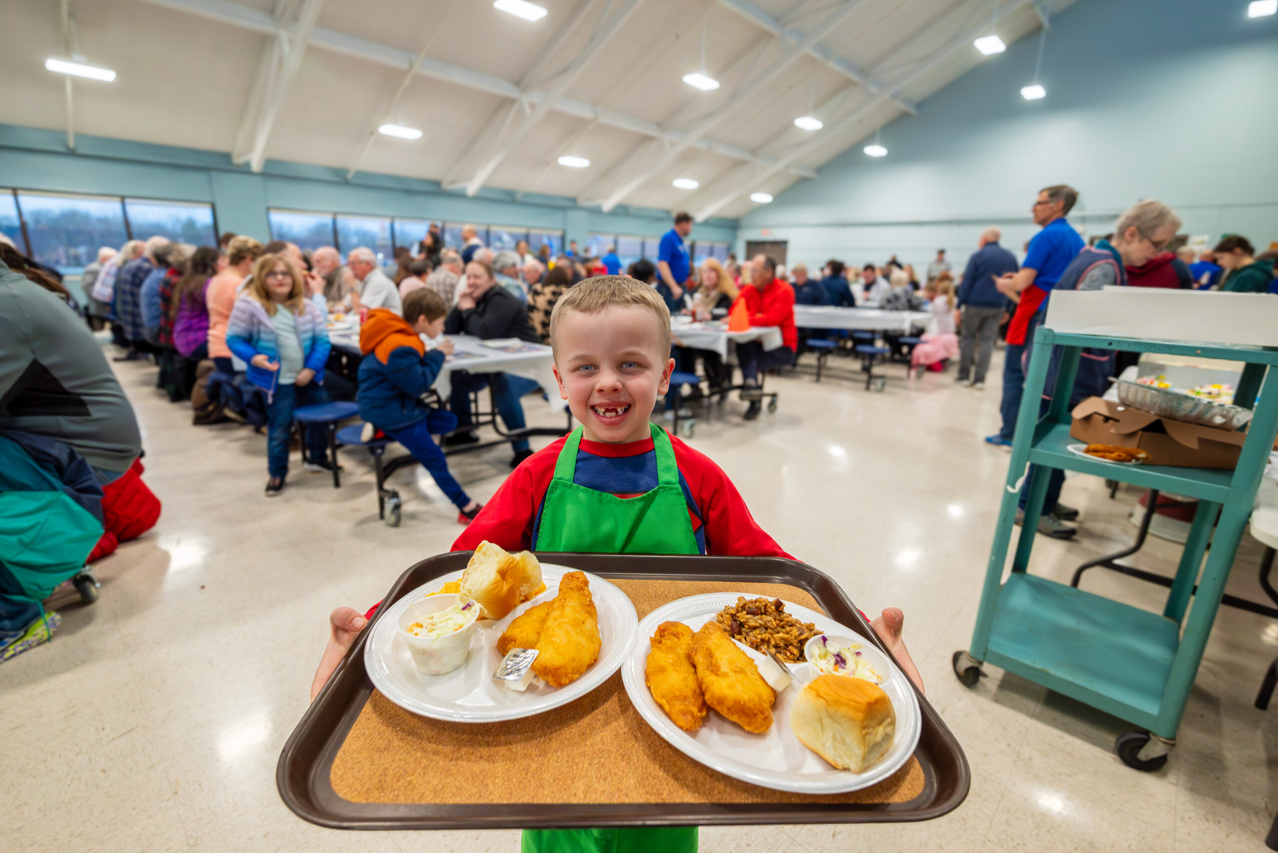 Six-year-old Benjamin Galio, the youngest and smallest server at St. Paul the Apostle Catholic Church's Lenten fish fry pauses for a moment to smile and have his picture taken before serving another group of diners. My Final Photo for March 1, 2024.