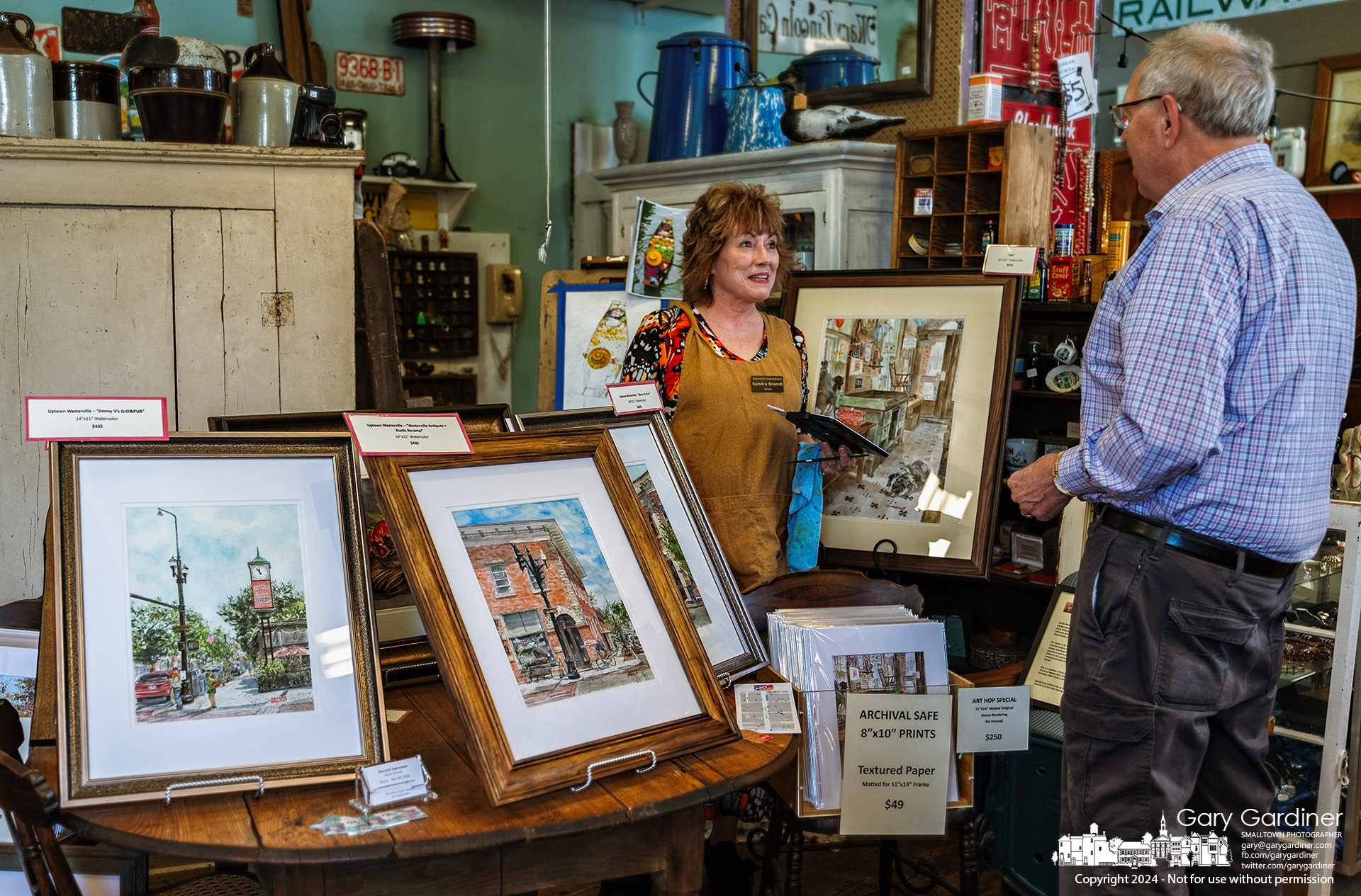 Artist Sandra Brandt pauses to talk with John Cameron from her spot in Westerville Antiques on Saturday afternoon at the Art Hop in Uptown Westerville. My Final Photo for April 20, 2024.