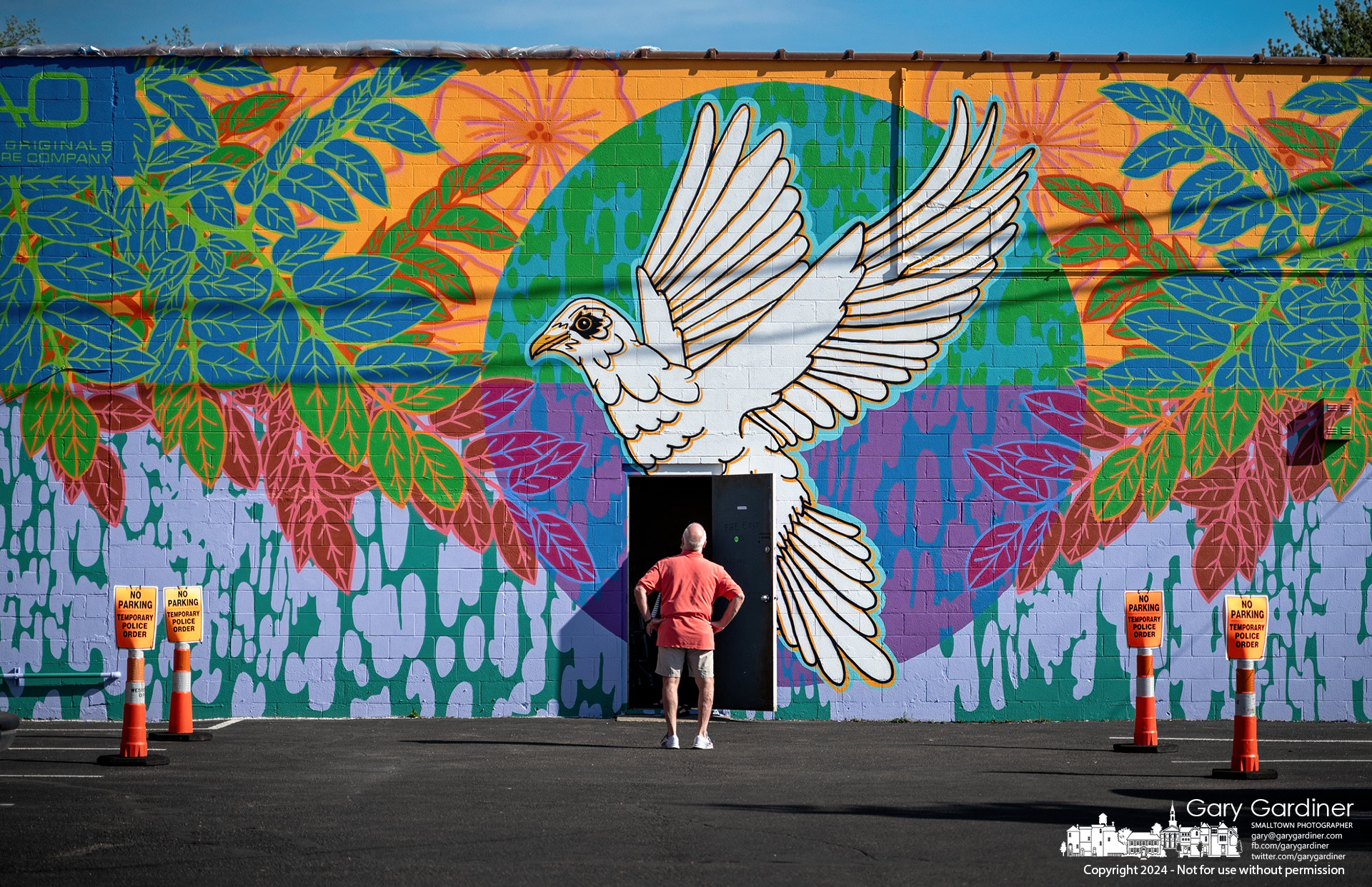 An Amish Originals worker surveys the completed "Peace" mural on the side of the furniture store's building. My Final Photo for April 29, 2024.