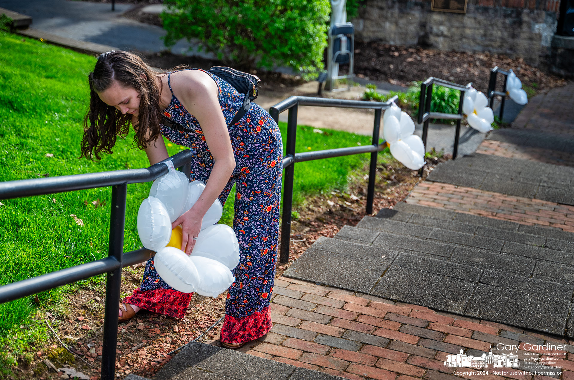 Otterbein student Lillian Moregret attaches inflated flowers to the handrails at the Alum Creek Park Amphitheater where the school's Celebration of Service and Leadership award presentations will take place later in the day. My Final Photo for April 18, 2024.