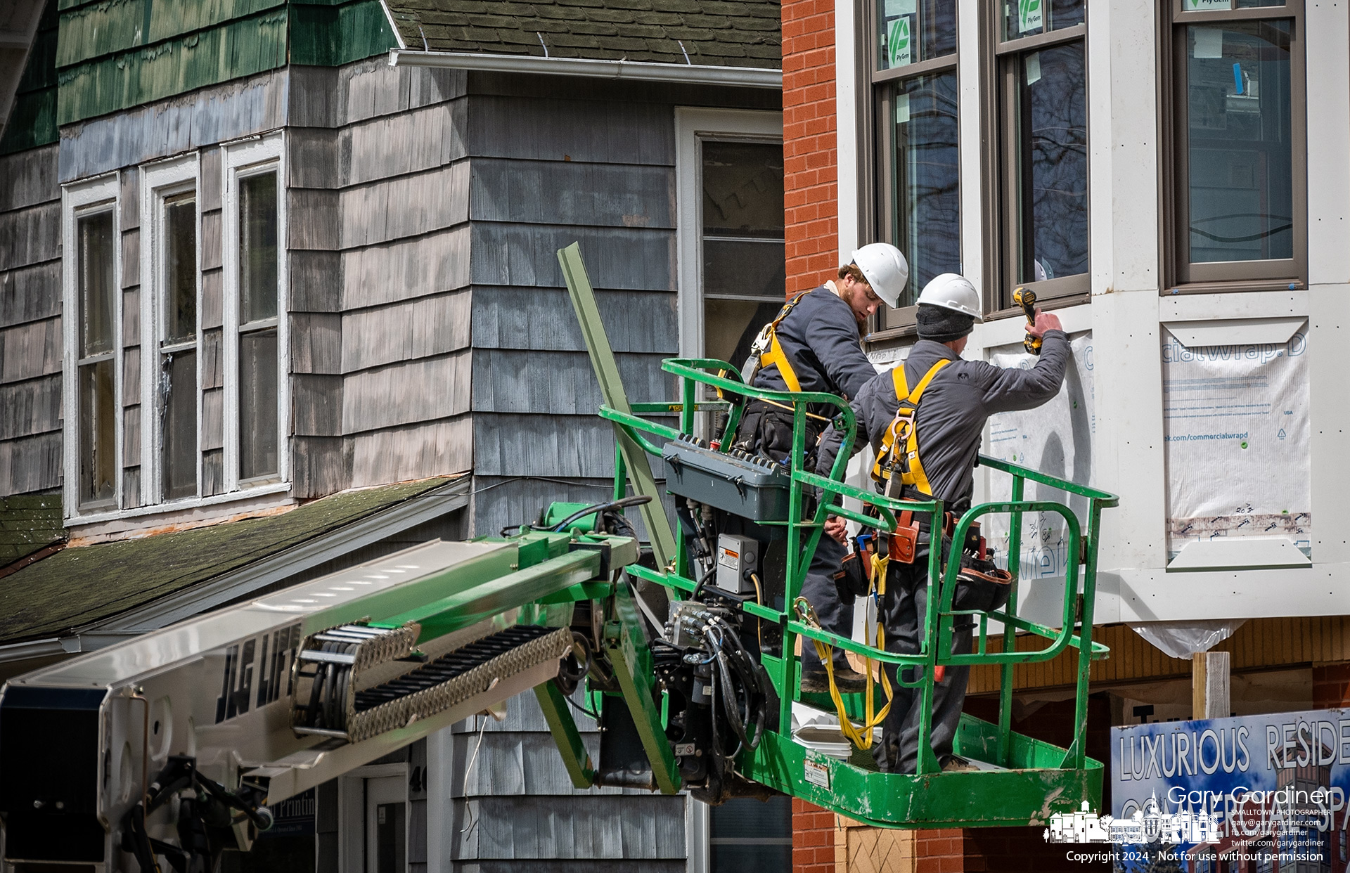 Workers install decorative trim around panels at the base of the windows of the apartment and business building under construction on West College in Uptown Westerville. My Final Photo for April 3, 2024.