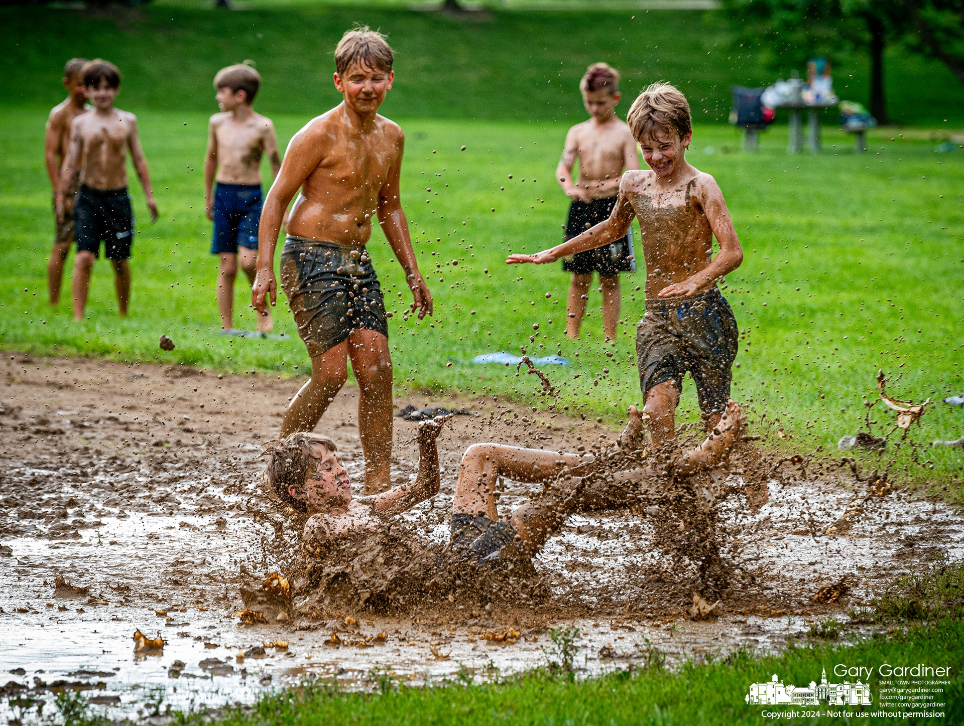 Boys take turns showing their best slides in the mud puddle between first and second bases on the Alum Creek Park North baseball field during a break from their friend's birthday party. My Final Photo for May 17, 2024.