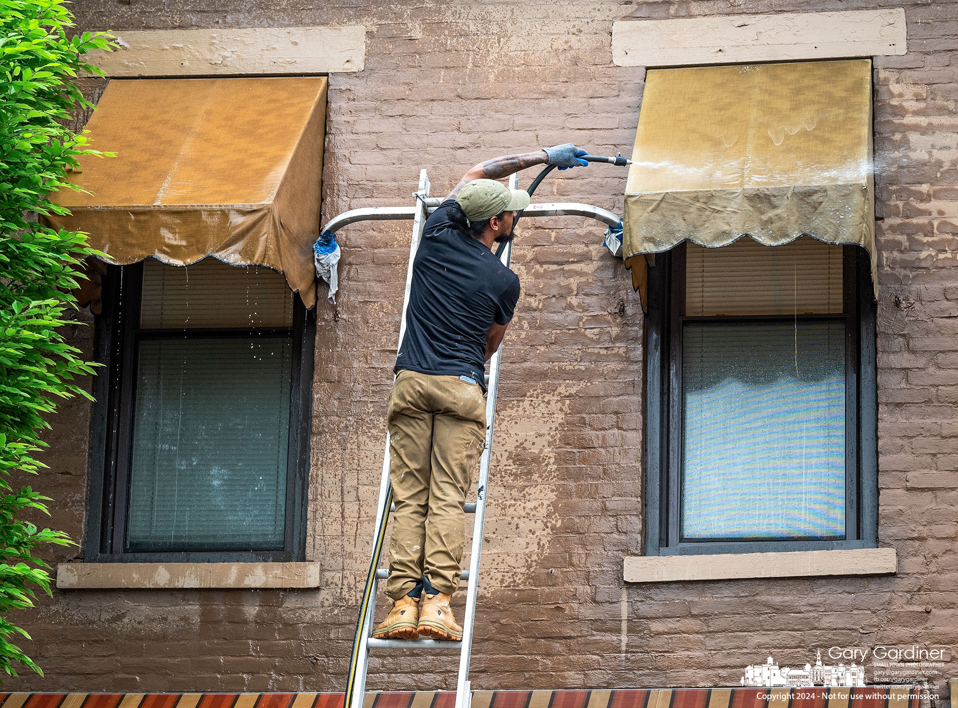 A set of awnings is sprayed with water to remove debris and grime after they were power-washed Friday on West College Uptown Westerville. My Final Photo for May 3, 2024.