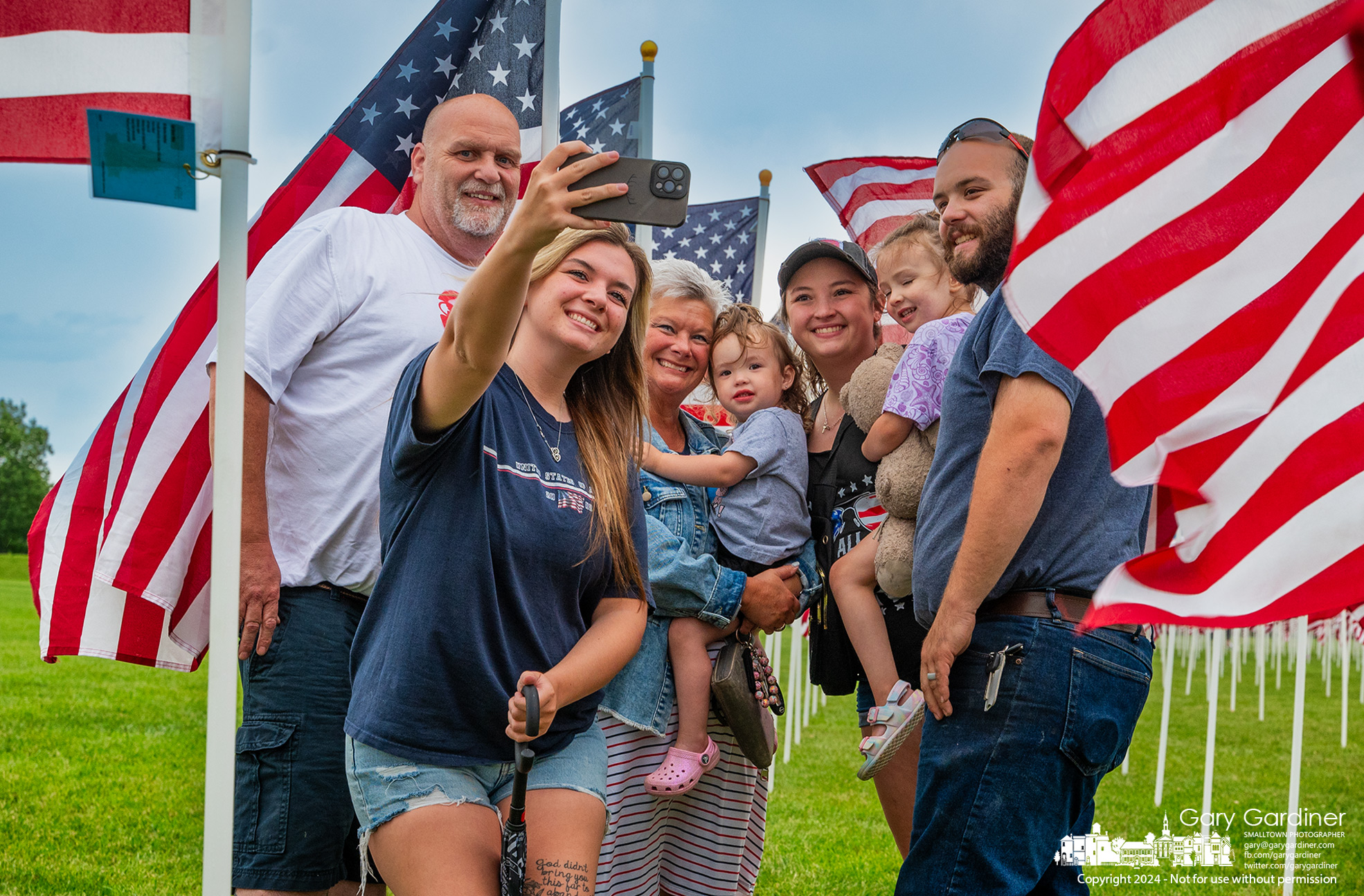 A family poses for a group photo at the flag dedicated at Field of Heroes in Westerville dedicated to the man who is the family's father, grandfather, and great-grandfather. My Final Photo for May 26, 2024.