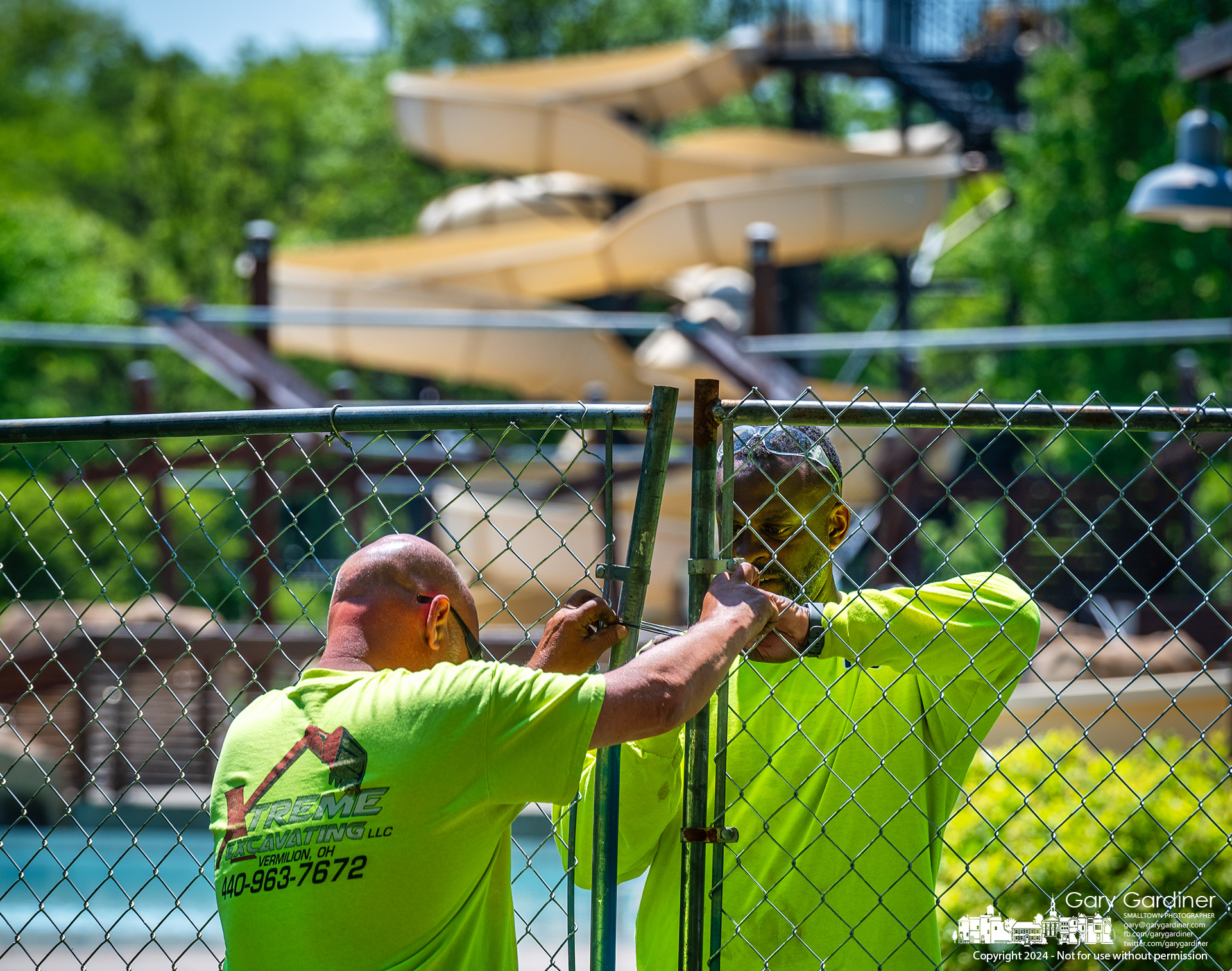 Brad Riggs, left, and R L Williamson join sections of temporary chain-link fencing around a portion of the Highlands pool area as they begin installing a taller, more secure fence to prevent people from entering the pool by climbing the fence. My Final Photo for May 13, 2024.