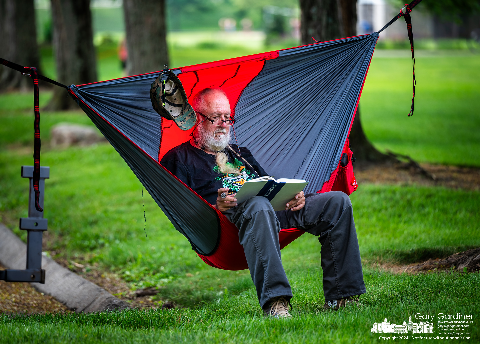 Russ Pederson enjoys a cigar, a book, the shade, and his hammock in the solitude of a corner of Alum Creek Park North away from the playground and fields and close to the rushing waters of the dam. My Final Photo for May 22, 2024.
