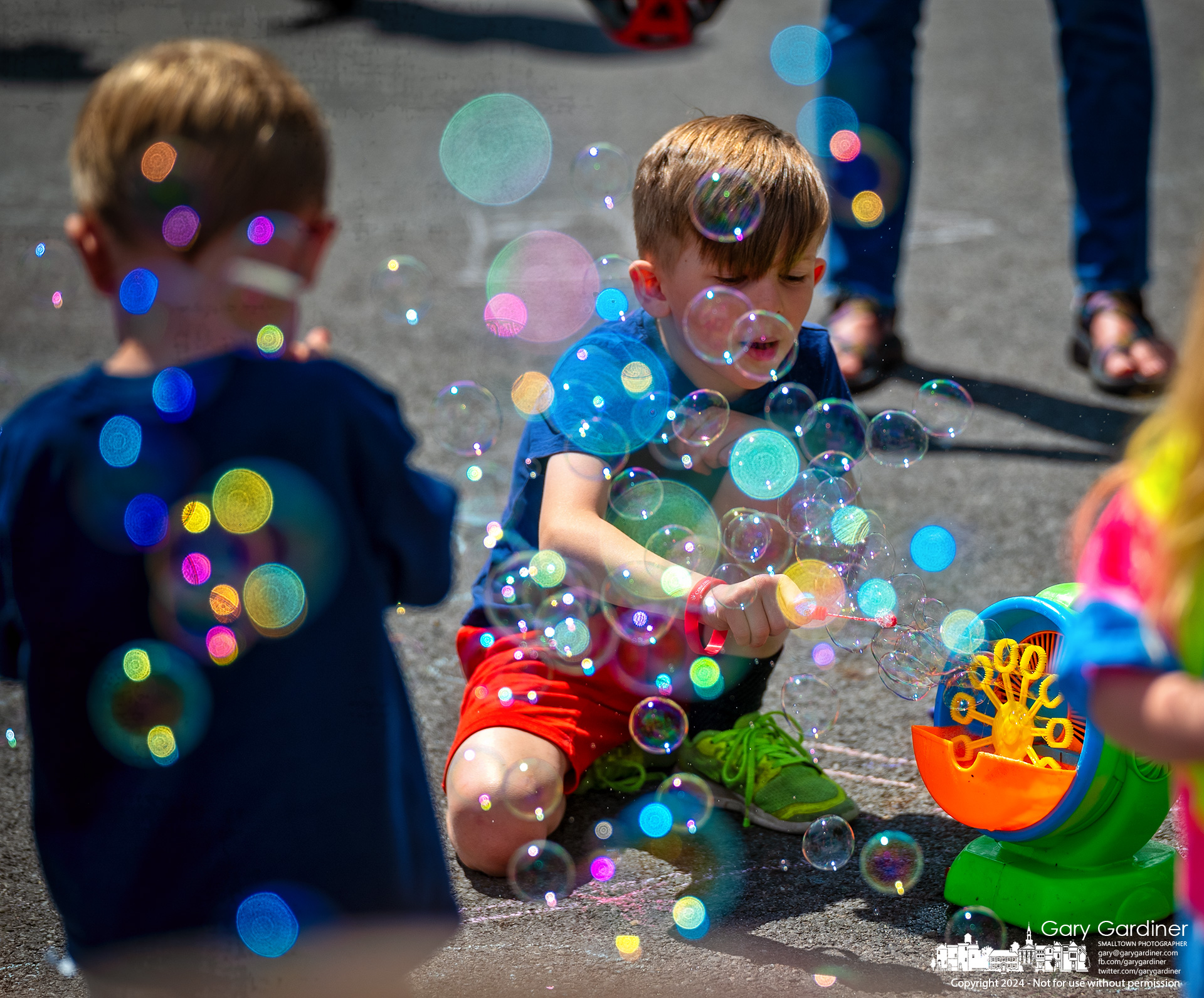 A young boy plays with bubbles blowing in the wind from the bubble machine in the youth corner of the Saturday Farmers Market in Uptown Westerville. My Final Photo for June 8, 2024.